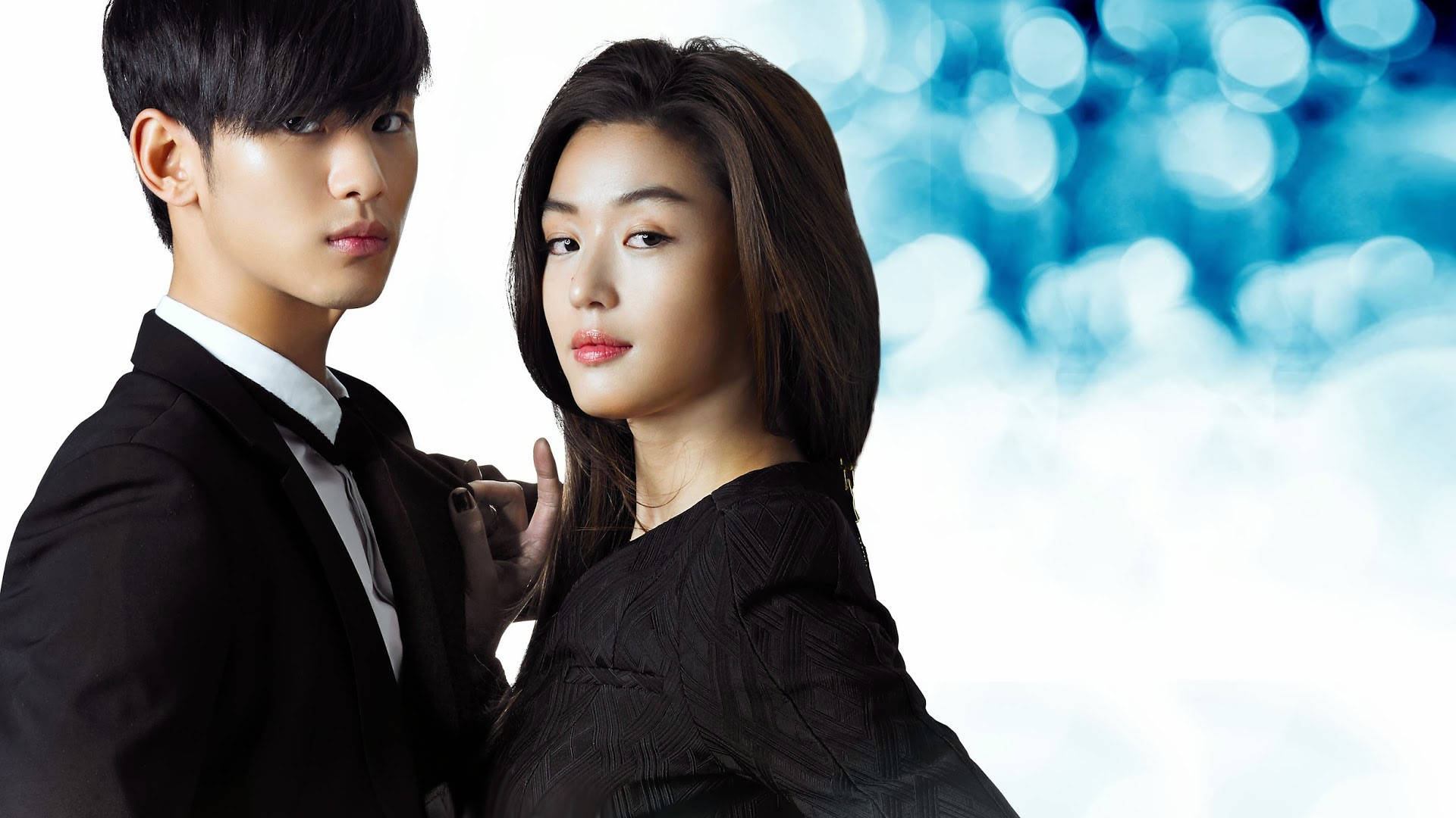 Jun Ji Hyun 桌布 壁紙 — 一對穿著黑色正式服裝的時尚情侶，在發光的藍色散景背景下親密擺姿勢。