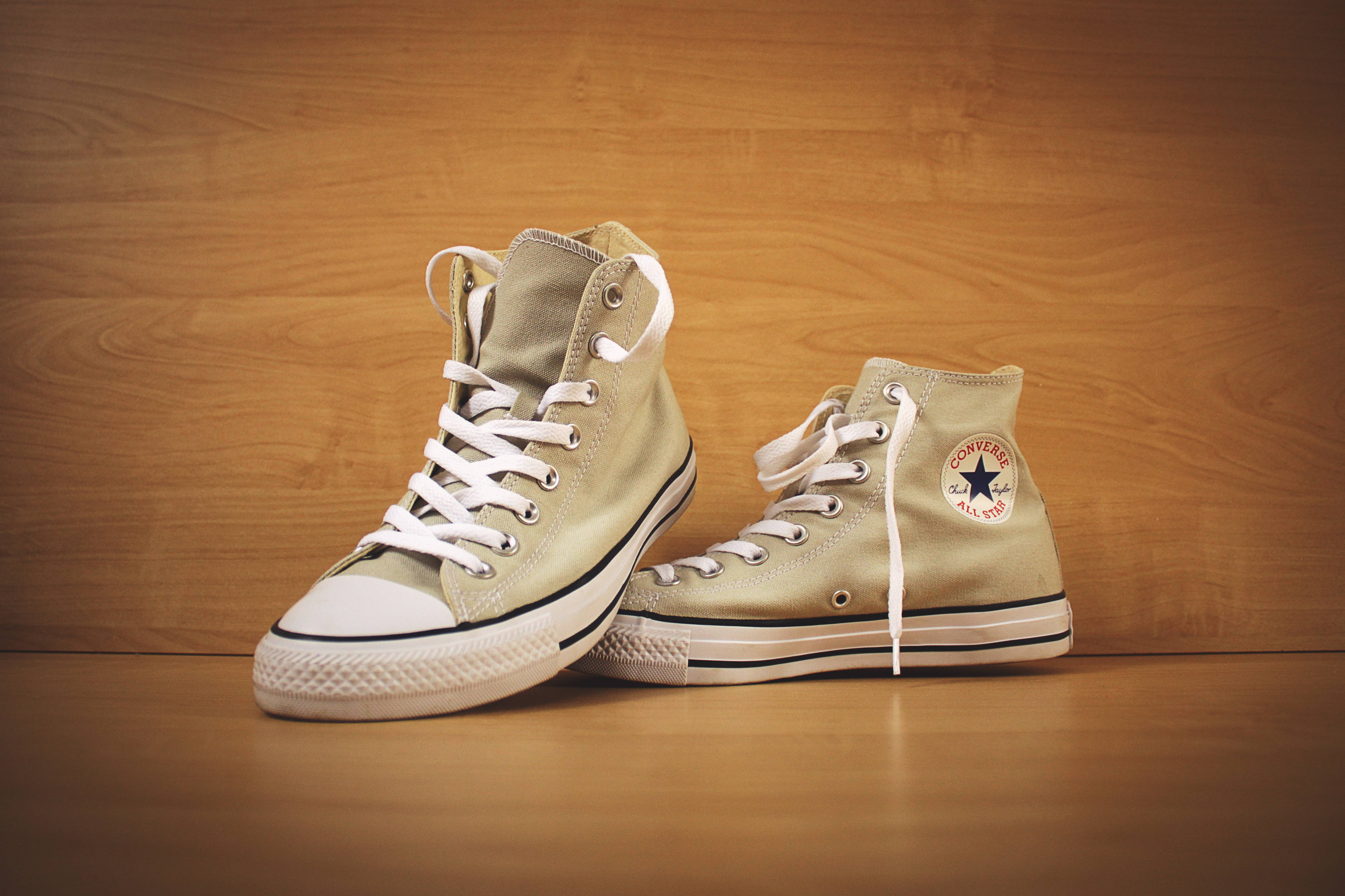 Converse 桌布 壁紙 — 一對米色高筒Converse運動鞋，搭配白色鞋帶，放置在溫暖的木地板上，背景是相襯的木牆。