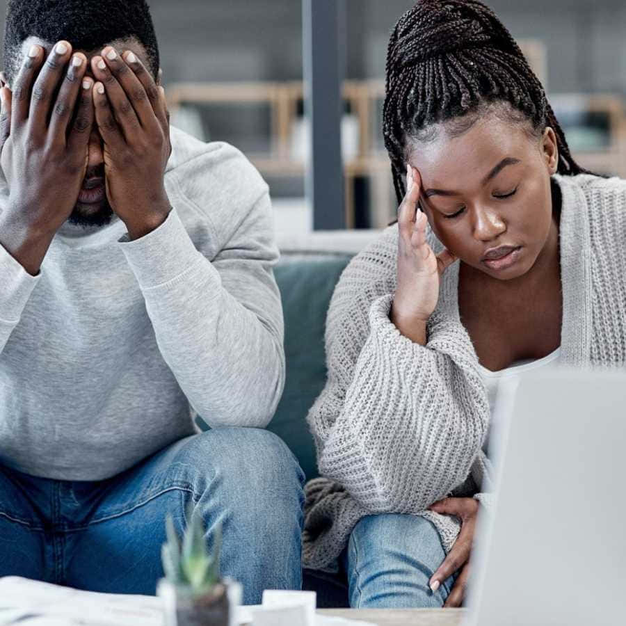 Sad Couple 桌布 壁紙 — 一對苦惱的情侶坐在沙發上，對筆記型電腦上的某些事情做出沮喪和悲傷的反應。