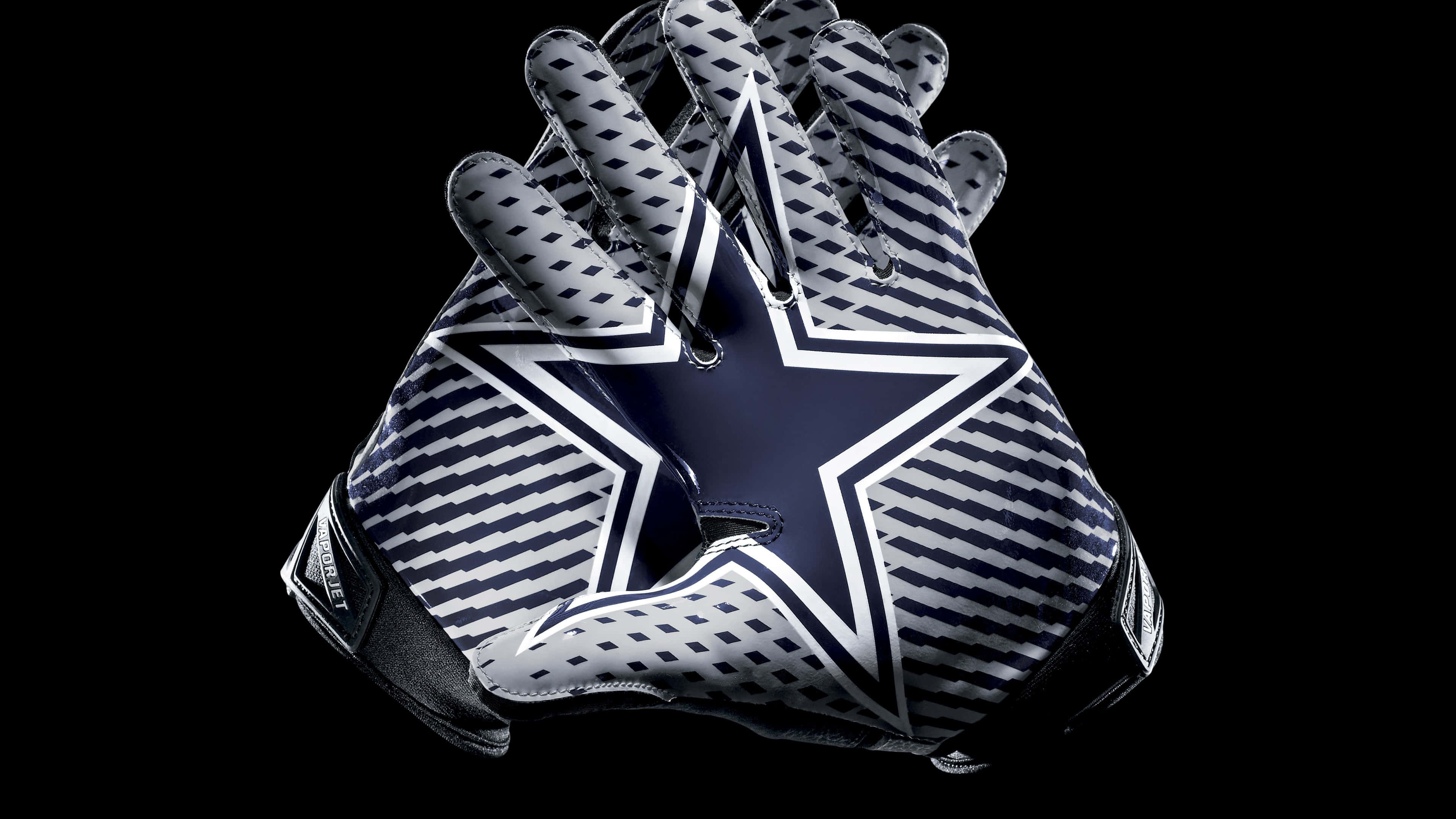 Dallas Cowboys Star 桌布 壁紙 — 一對達拉斯牛仔隊美式足球手套，帶有海軍藍星形標誌和白色斜紋，背景為黑色。