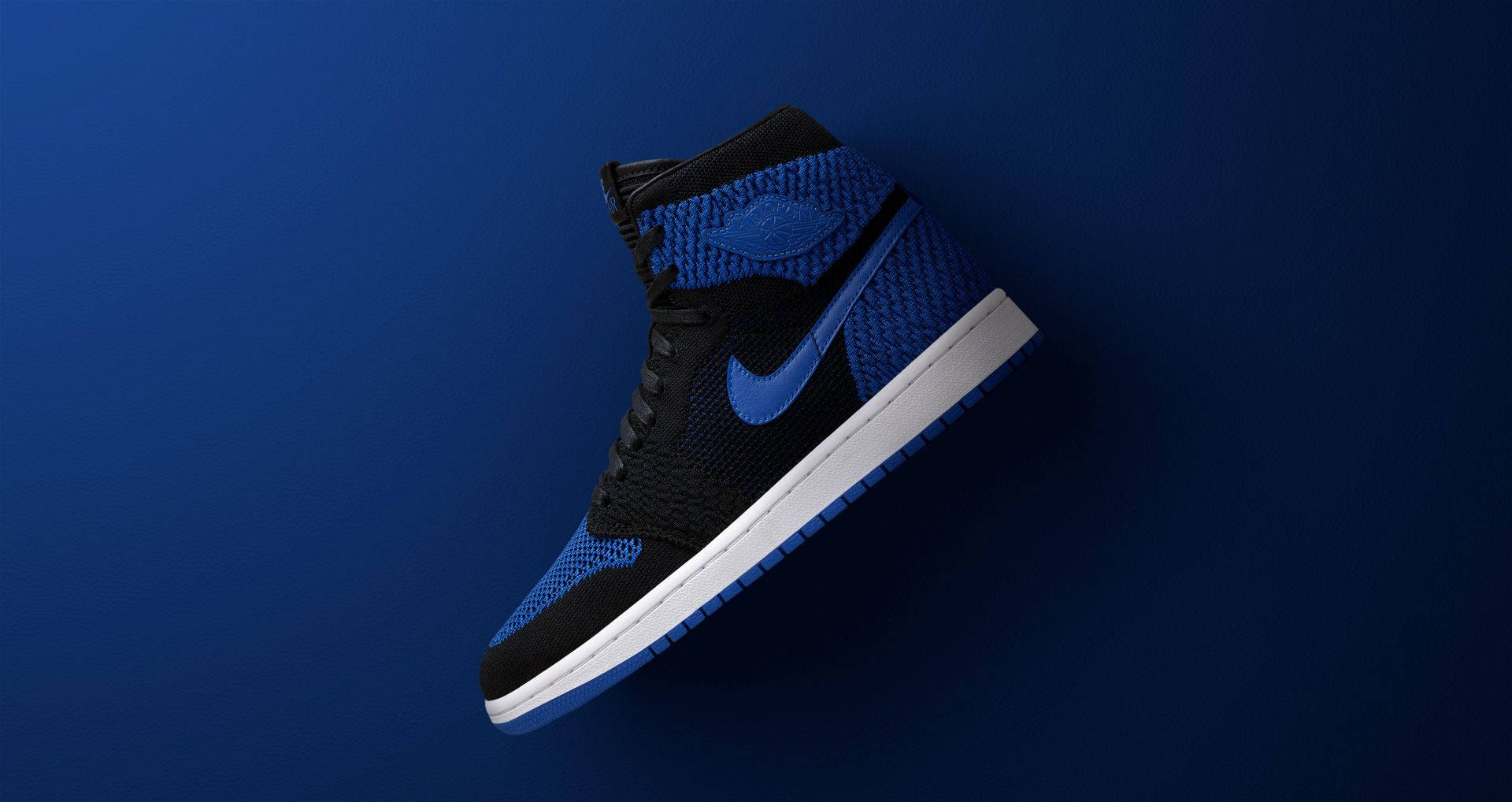 一雙黑色和藍色的高筒運動鞋，白色鞋底，放在藍色背景上。 — Air Jordan 1 壁紙