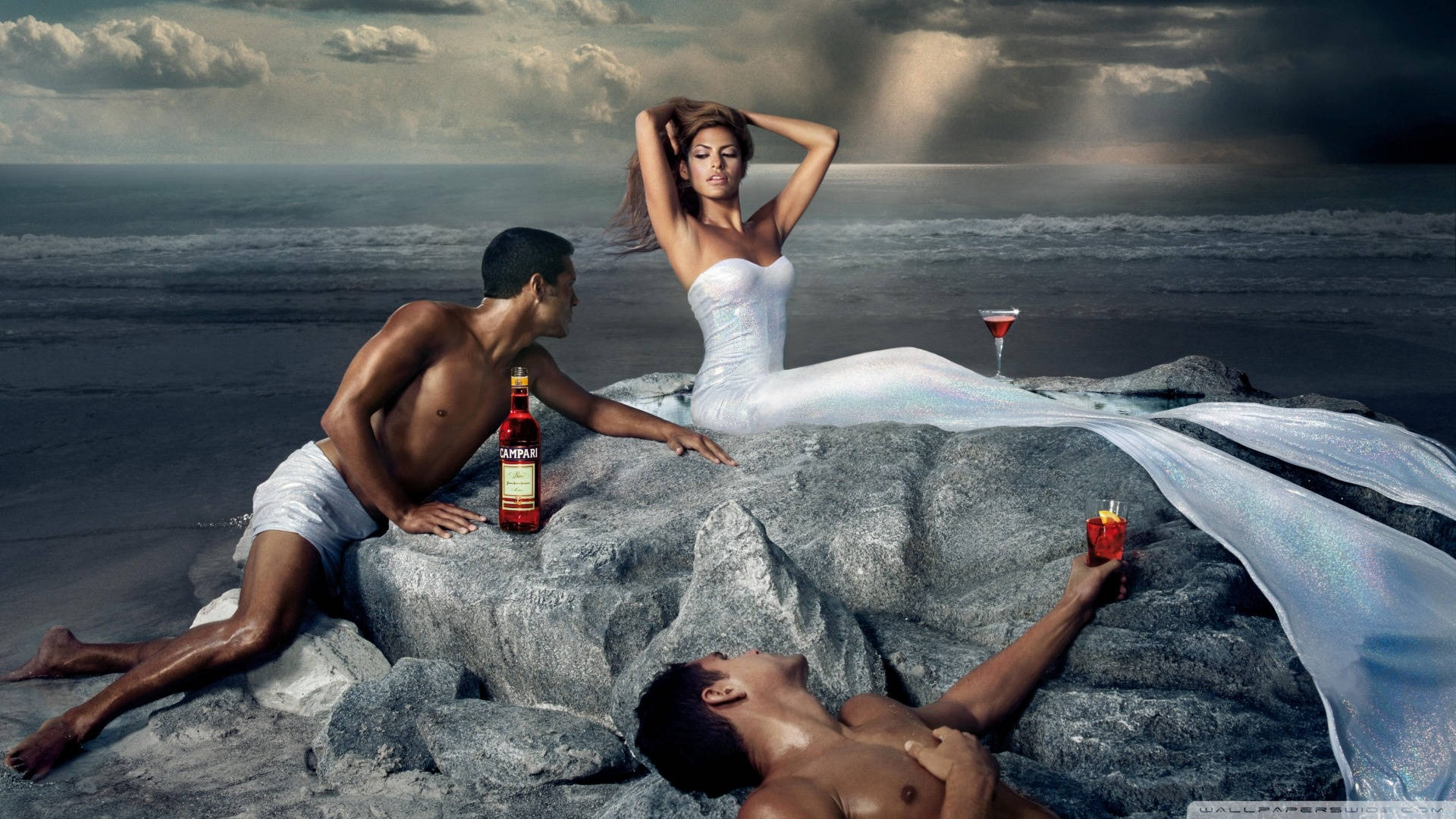 美女 桌布 壁紙 — 一對魅力情侶在風暴中的海洋岩石上休息，手持飲品和一瓶金芬黛，背景是戲劇性的雲層。