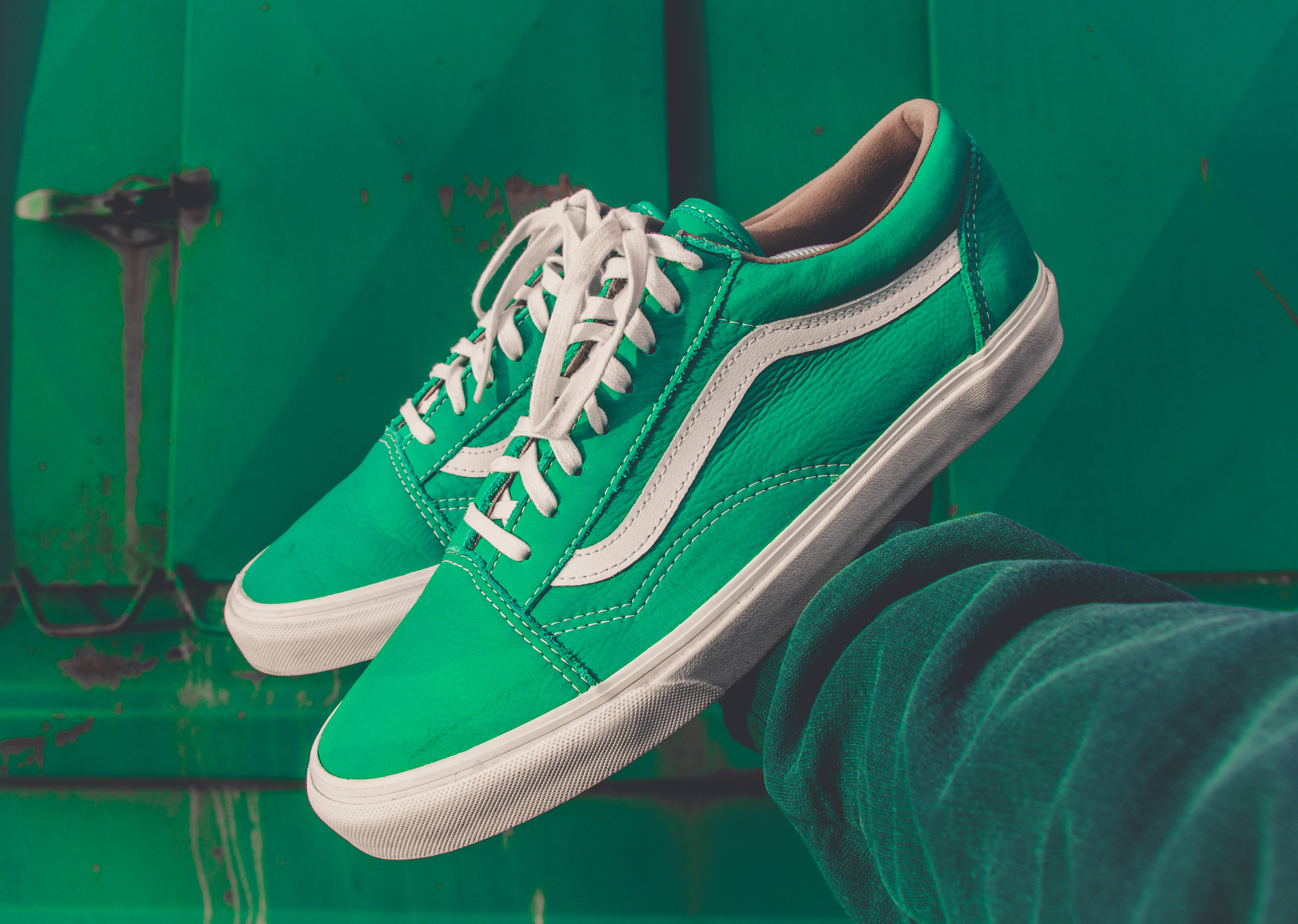 Vans 桌布 壁紙 — 一對鮮綠色Vans運動鞋，配有白色鞋帶和鞋底，靠在經風化的綠色金屬背景上。