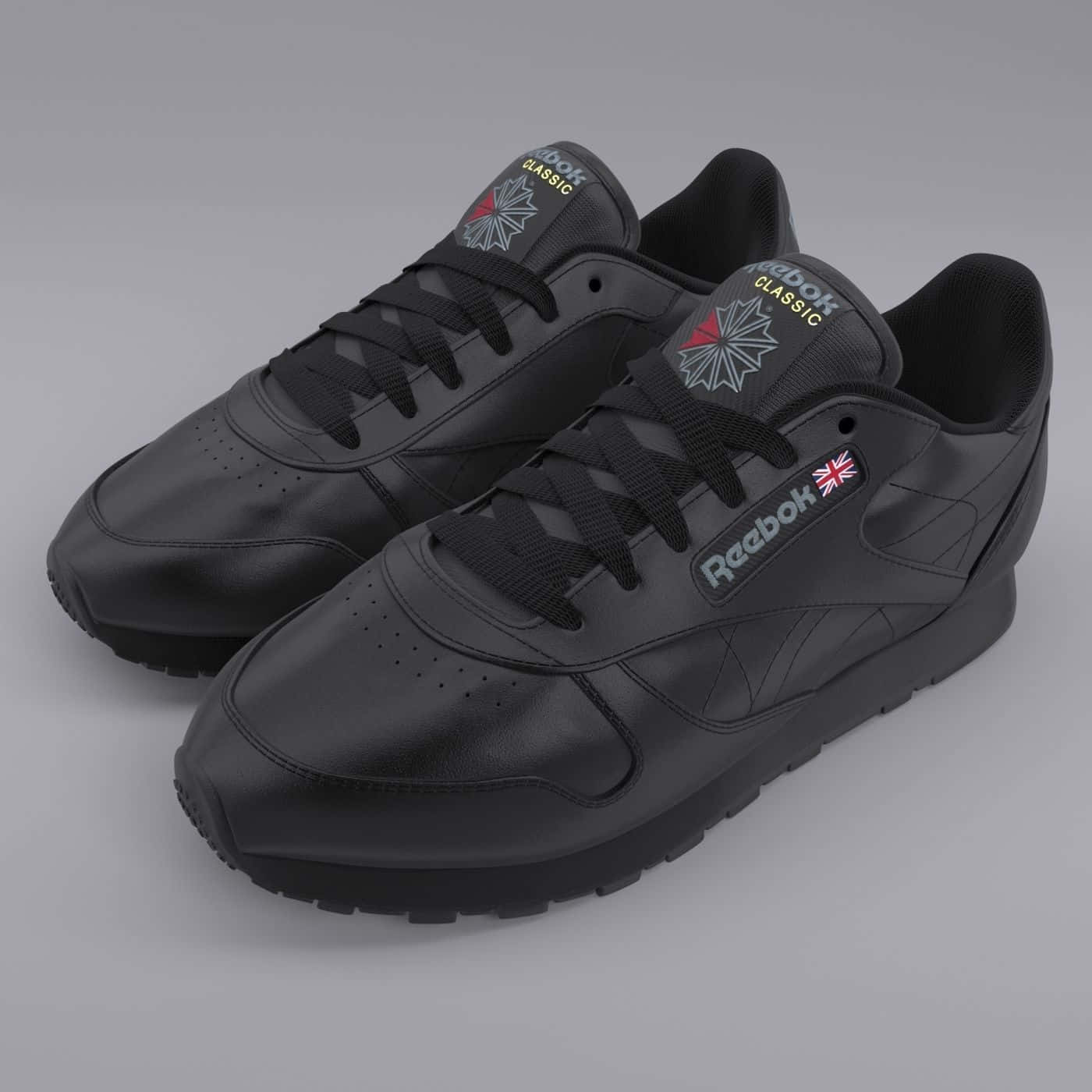 銳步 桌布 壁紙 — 一對黑色Reebok Classic運動鞋，帶有微妙的紅色和灰色點綴，在灰色中性背景上展示。