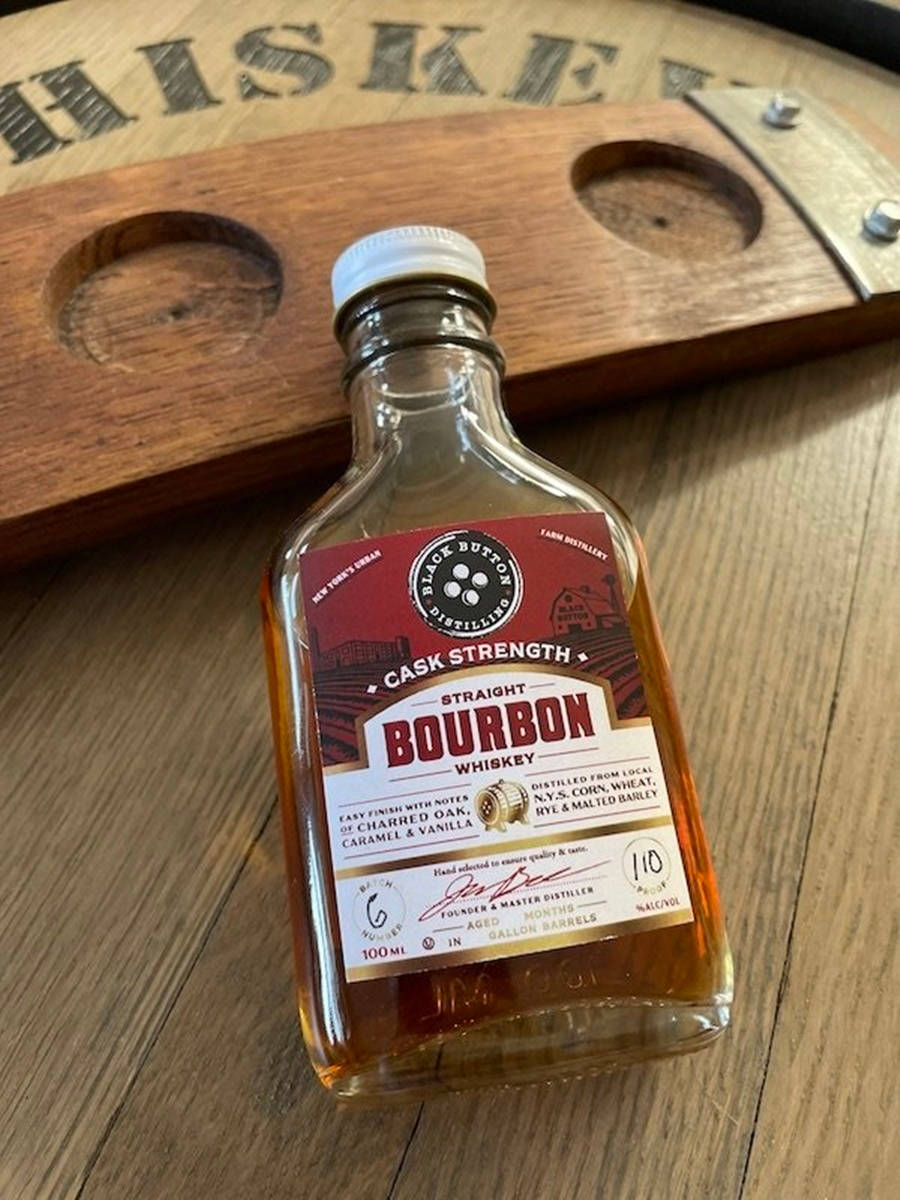 bottle 桌布 壁紙 — 一小瓶 Black Button Cask Strength 波本威士忌放在木桌上，旁邊有一個威士忌桶杯墊。