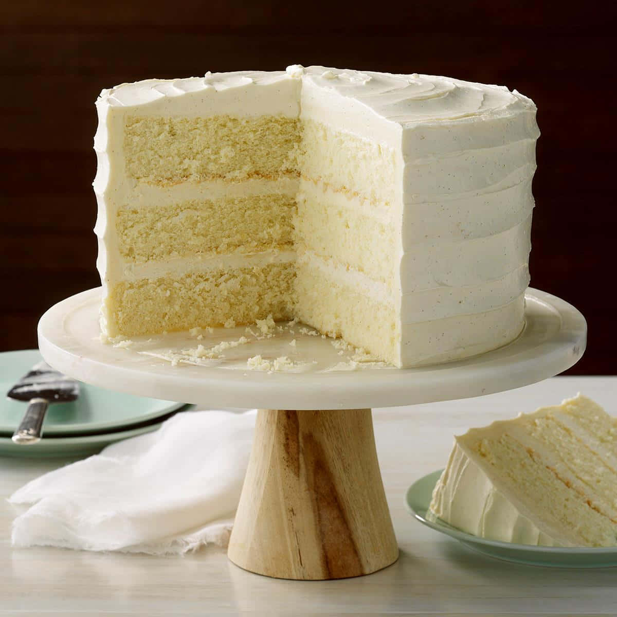 Buttercream 桌布 壁紙 — 一層層的香草蛋糕配上白色糖霜，放在木架上，旁邊盤子裡有一片蛋糕。