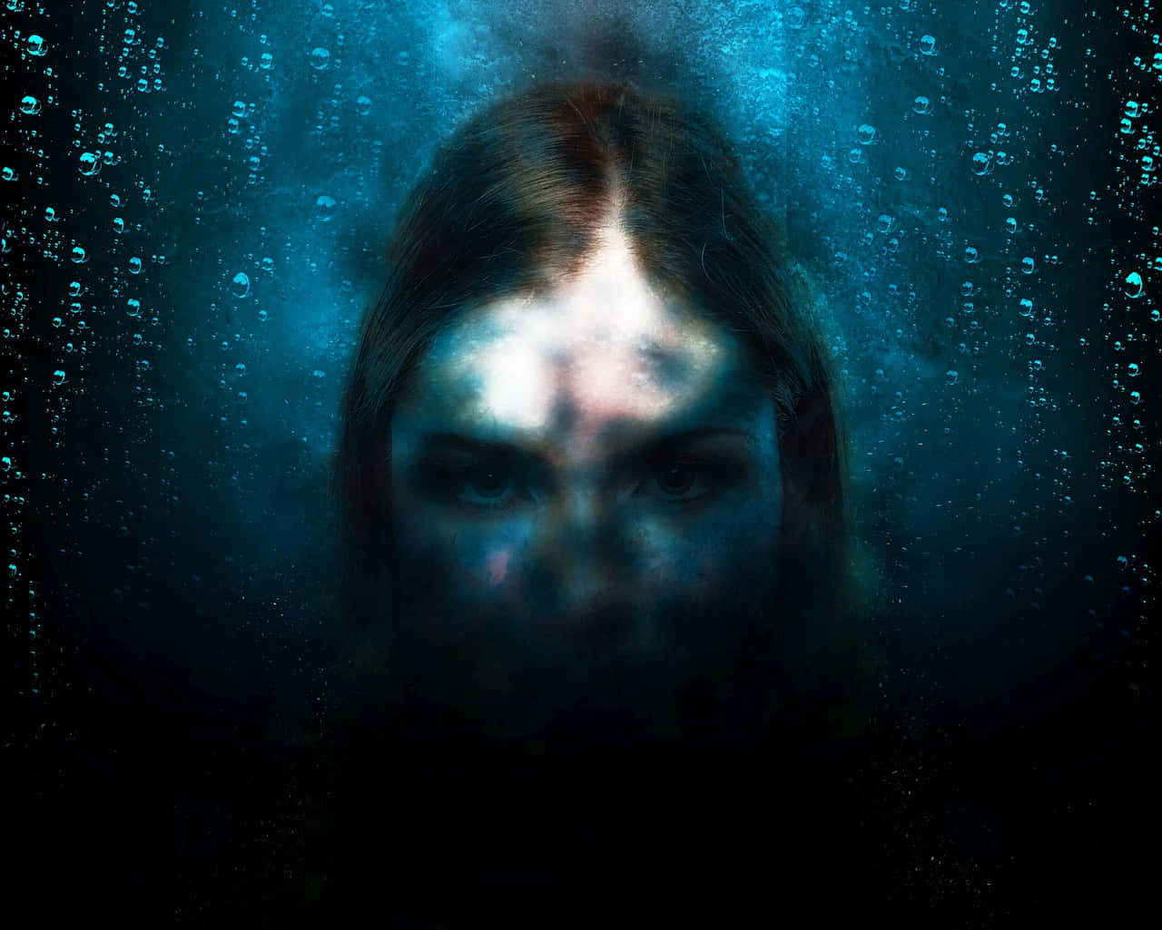 Scary Underwater 桌布 壁紙 — 一幅令人難忘的水下肖像，描繪一位女性的臉龐被一道光束照亮，周圍環繞著氣泡和深藍色的海水。