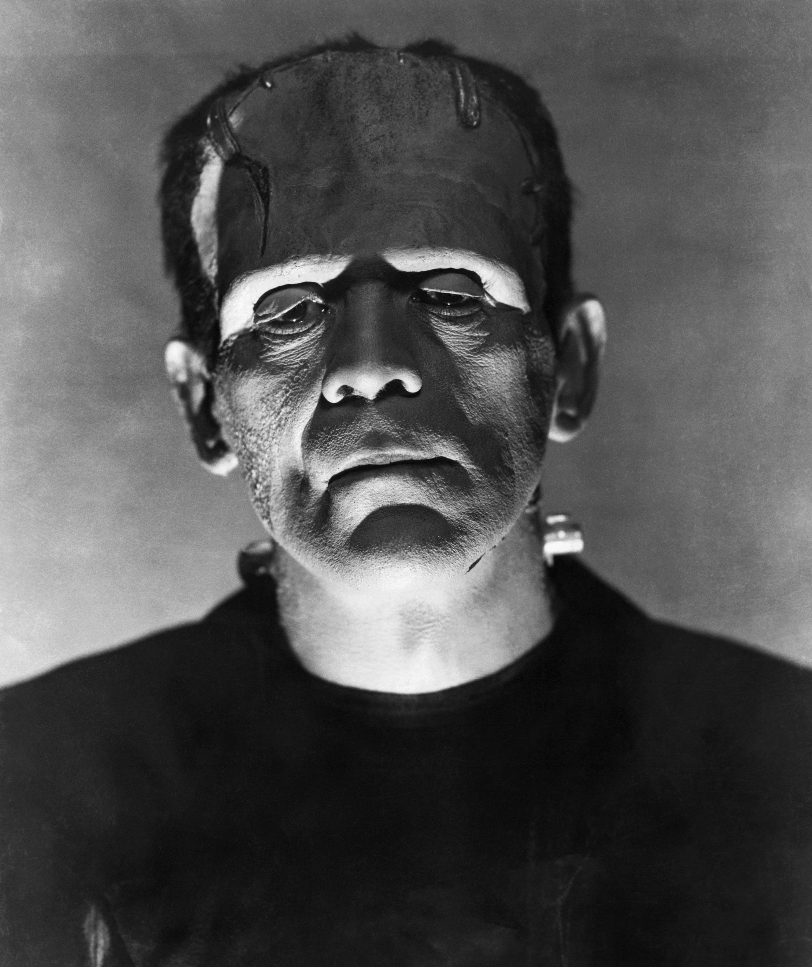 horror villains 桌布 壁紙 — 一幅令人難忘的黑白肖像，描繪標誌性的科學怪人怪物，帶有可見的縫合和螺栓，背景樸素。