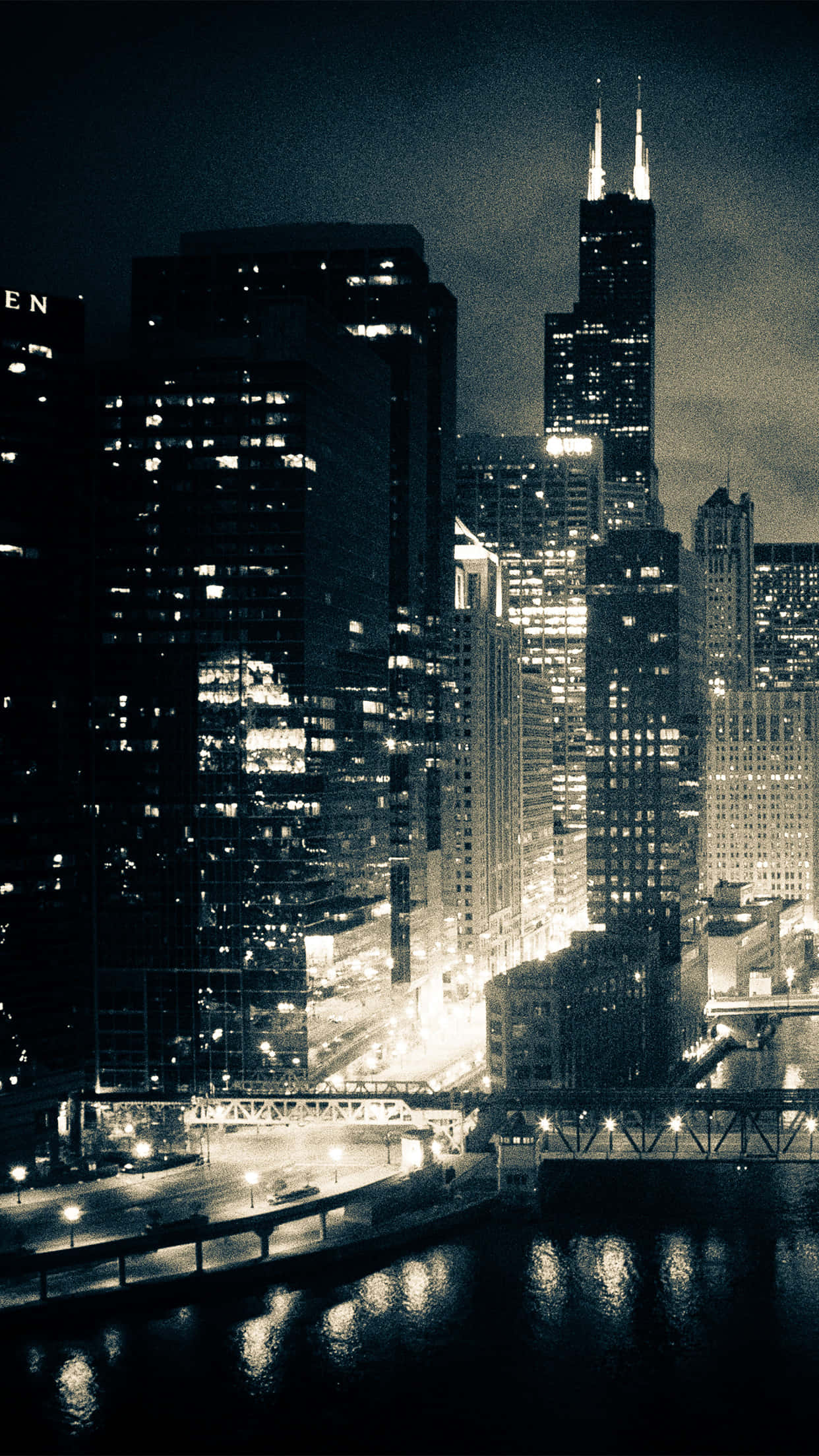 Chicago City Night 桌布 壁紙 — 一幅充滿憂鬱氣息的棕褐色調夜景，高聳的摩天大樓將燈光倒映在下面的河流上。