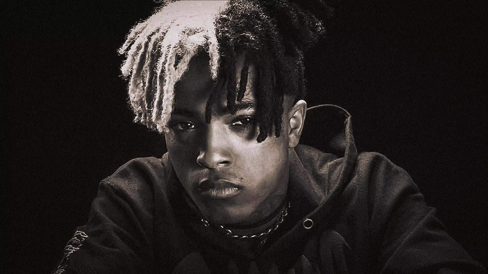 XXXTENTACION 桌布 壁紙 — 一幅充滿氣氛的黑白肖像，一名年輕男子留著一半漂白的辮子，在黑暗背景下強烈凝視。