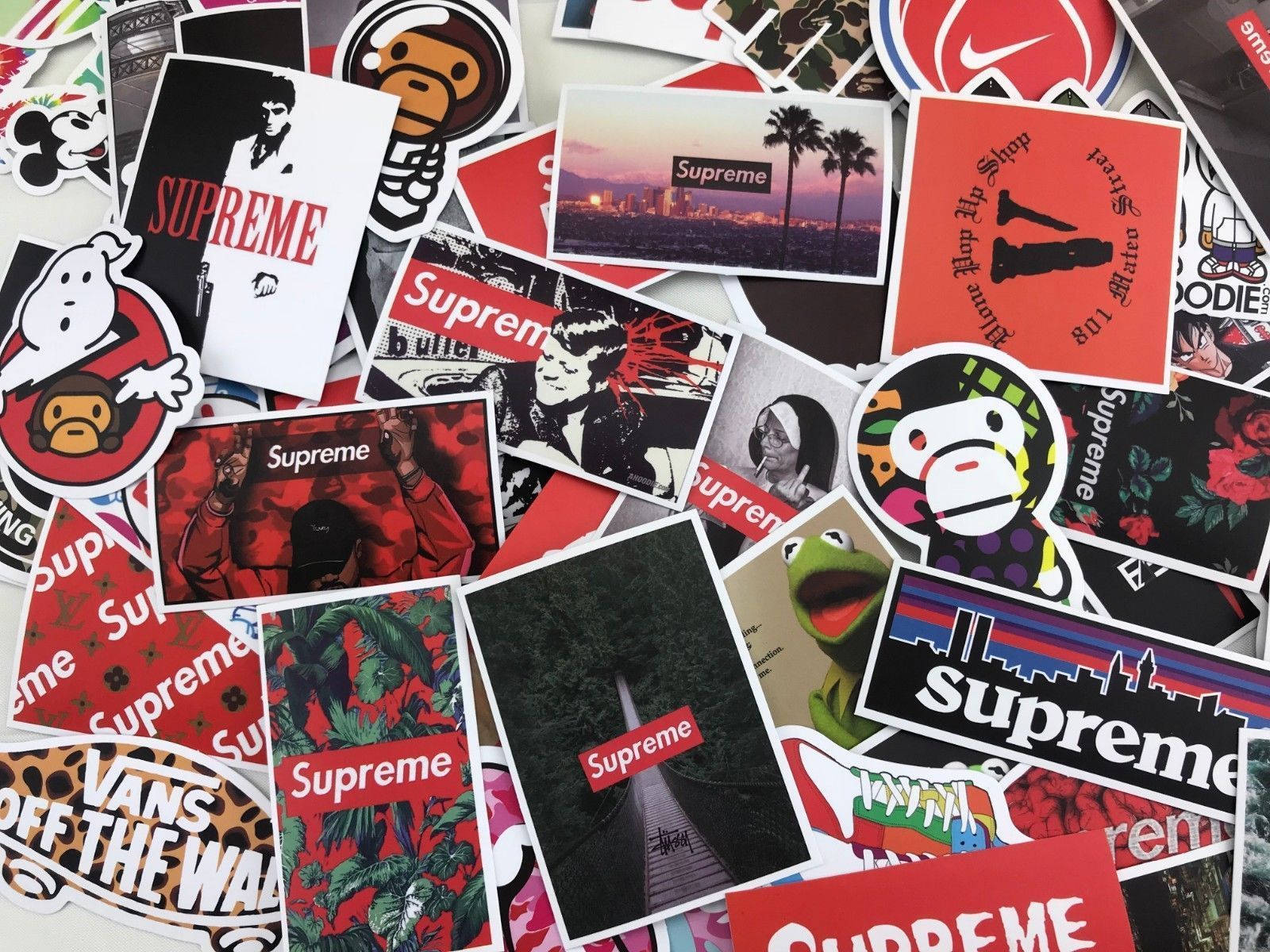 stickers 桌布 壁紙 — 一幅充滿活力的Supreme品牌貼紙拼貼畫，包含標誌、角色和城市景觀散落在表面上。