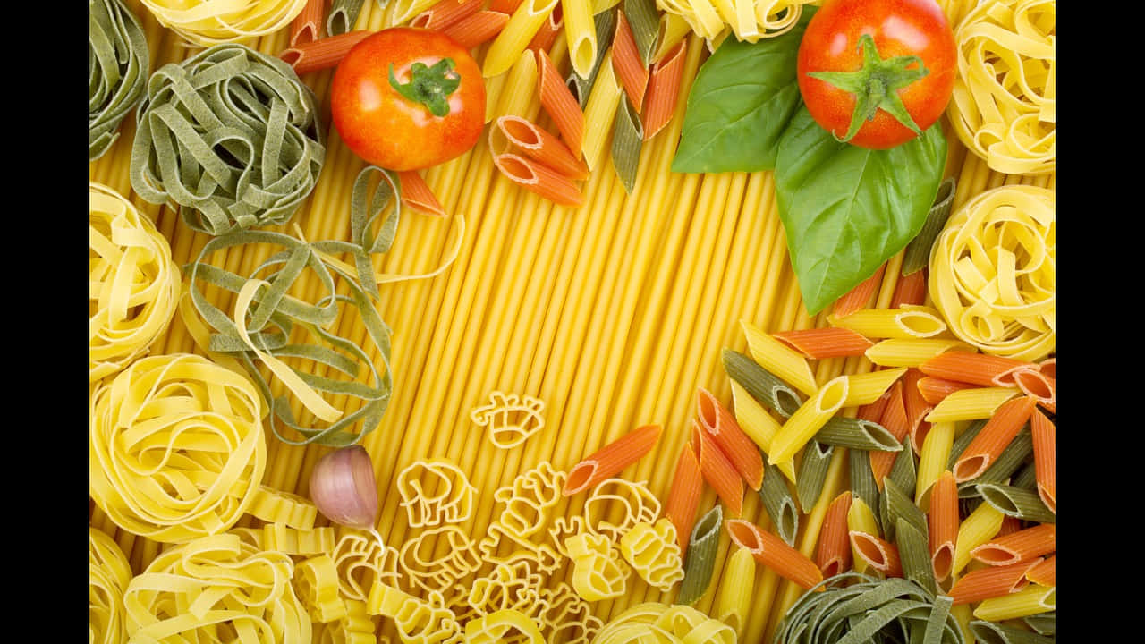 720p Pasta 桌布 壁紙 — 一幅充滿活力的俯拍照片，展示了各種色彩繽紛的義大利麵，排列成邊框，圍繞著中央的義大利麵床，配以新鮮番茄和羅勒葉。