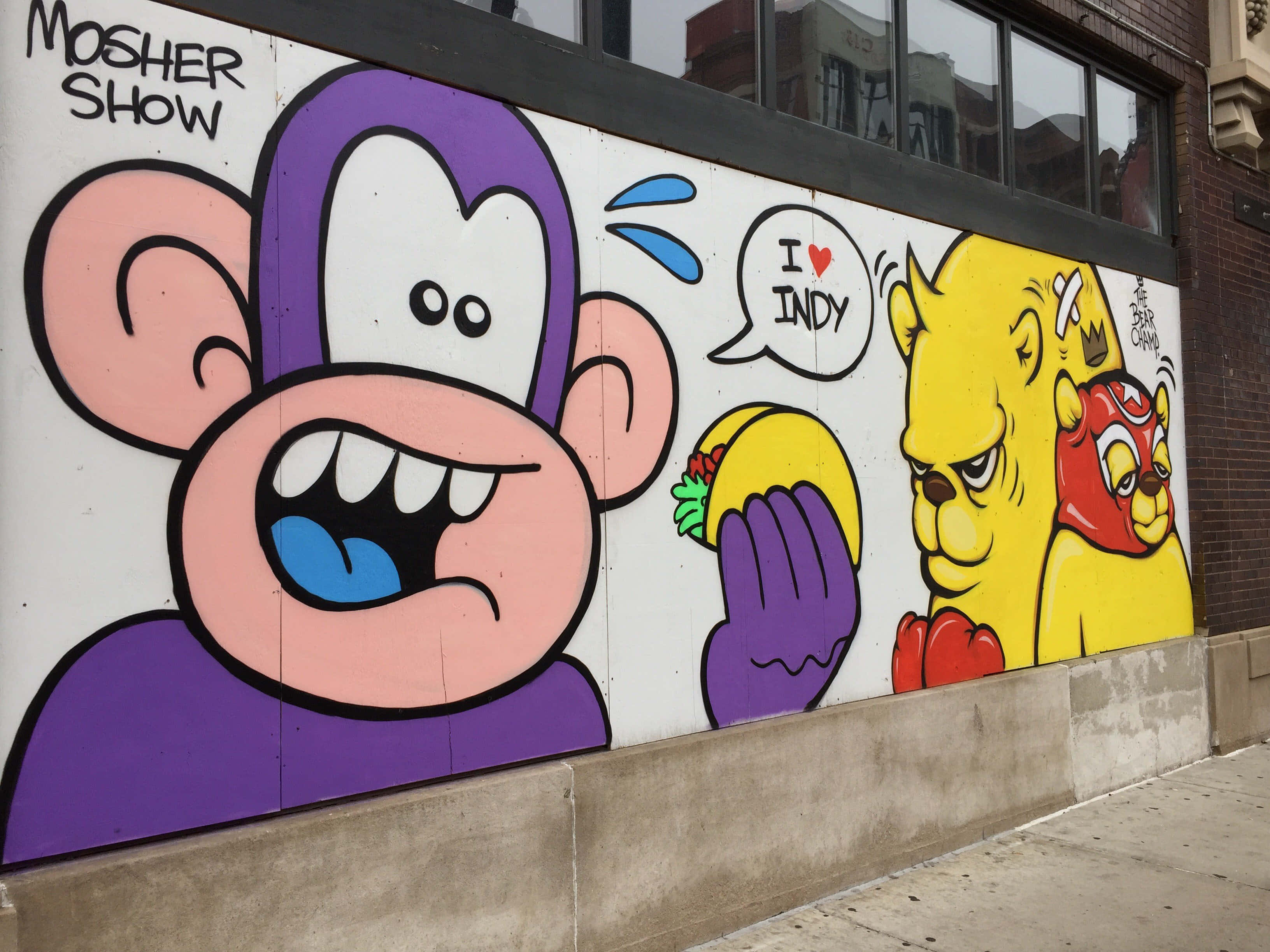 Graffiti Art 桌布 壁紙 — 一幅充滿活力的卡通塗鴉壁畫，描繪了城市牆上的一隻紫色猴子和黃色角色，並帶有「MOSHER SHOW」文字。