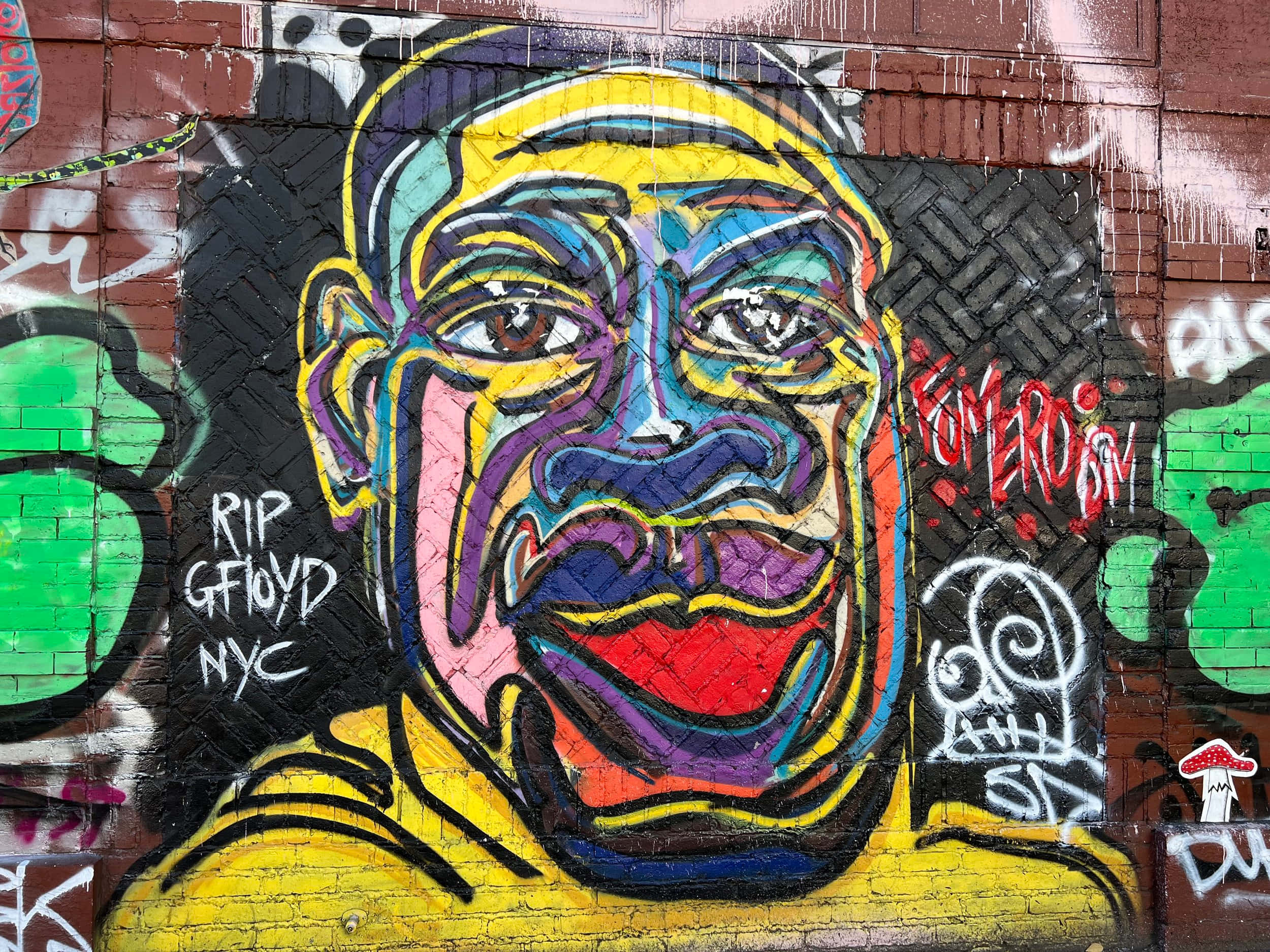 Graffiti Art 桌布 壁紙 — 一幅充滿活力的塗鴉壁畫，在磚牆上繪有風格化的臉孔，色彩大膽，周圍佈滿塗鴉標籤。