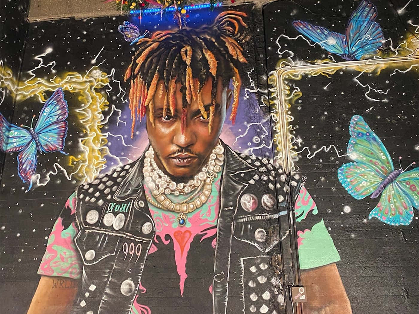 塗鴉壁畫，描繪一名有辮子頭的男子和蝴蝶在宇宙場景中。 — Juice Wrld 壁紙