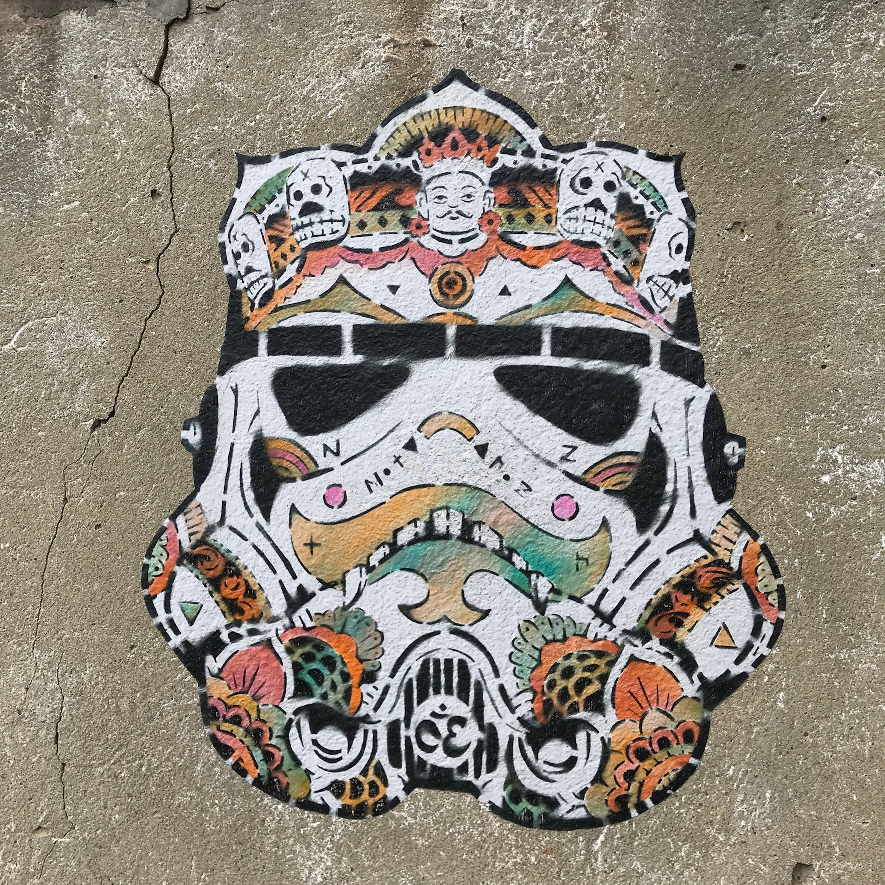 星際大戰 桌布 壁紙 — 一幅充滿活力的塗鴉壁畫，描繪了一個裝飾著骷髏頭和華麗圖案的風暴兵頭盔，畫在裂開的混凝土上。