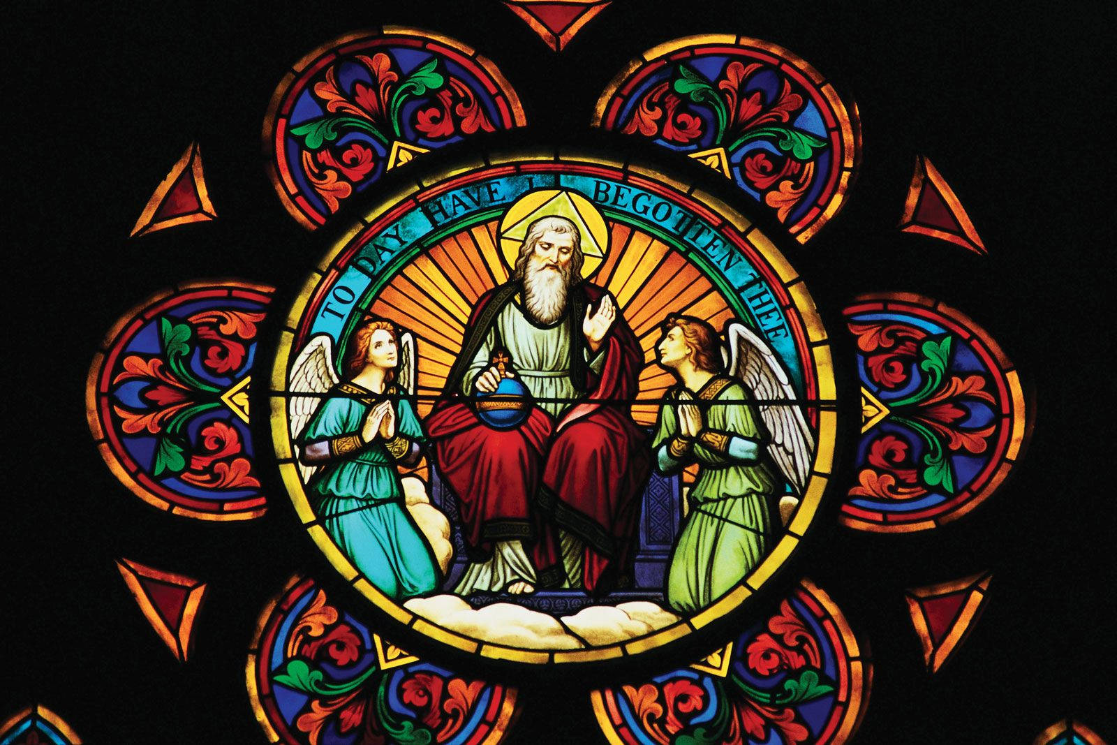 教堂 桌布 壁紙 — 一幅充滿活力的彩繪玻璃窗描繪了一位留鬍鬚的中心人物與天使，周圍環繞著華麗的花卉圖案和耀眼的光芒。