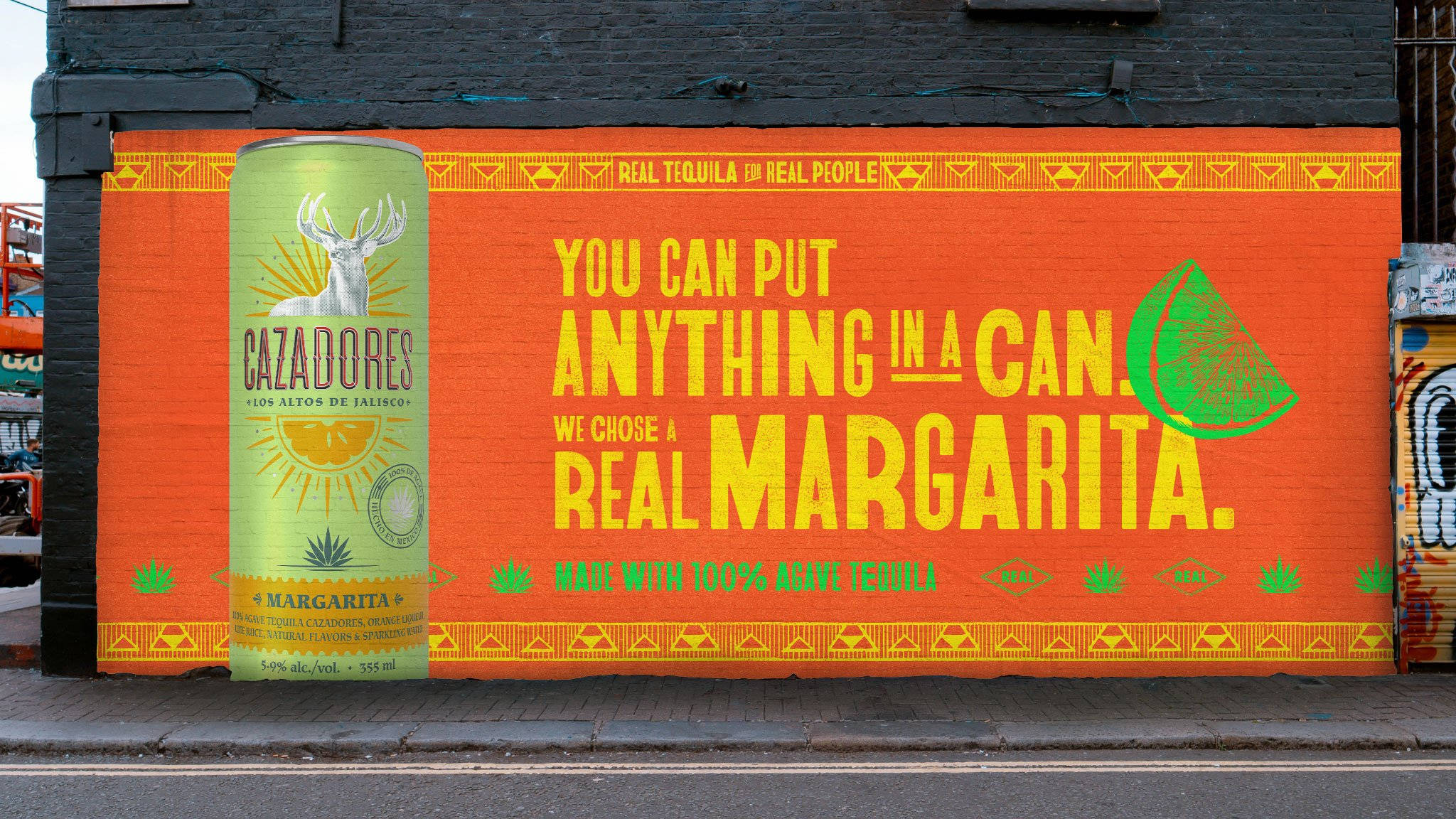 margaritas 桌布 壁紙 — 一幅充滿活力的橙色壁畫，在磚牆上以醒目的黃色文字和綠色龍舌蘭裝飾推廣Cazadores瑪格麗特酒。