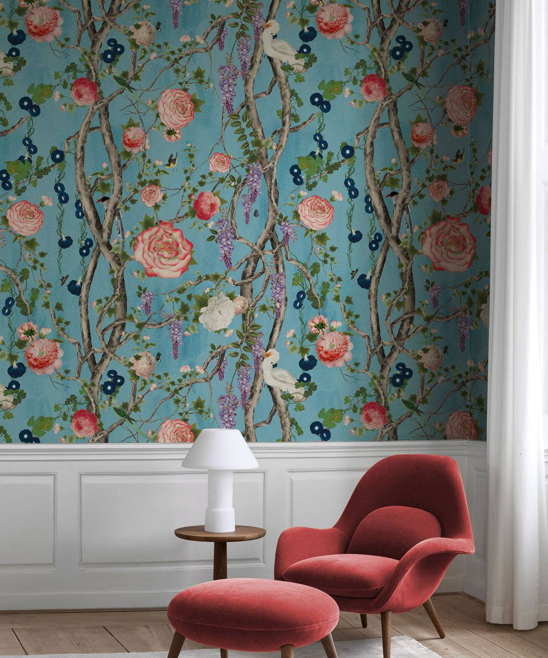 Chinoiserie 桌布 壁紙 — 一幅充滿活力的花卉壁紙，上面有粉紅玫瑰、紫色紫藤和藍色漿果，裝飾在豪華紅色扶手椅和擱腳凳後面的牆上。