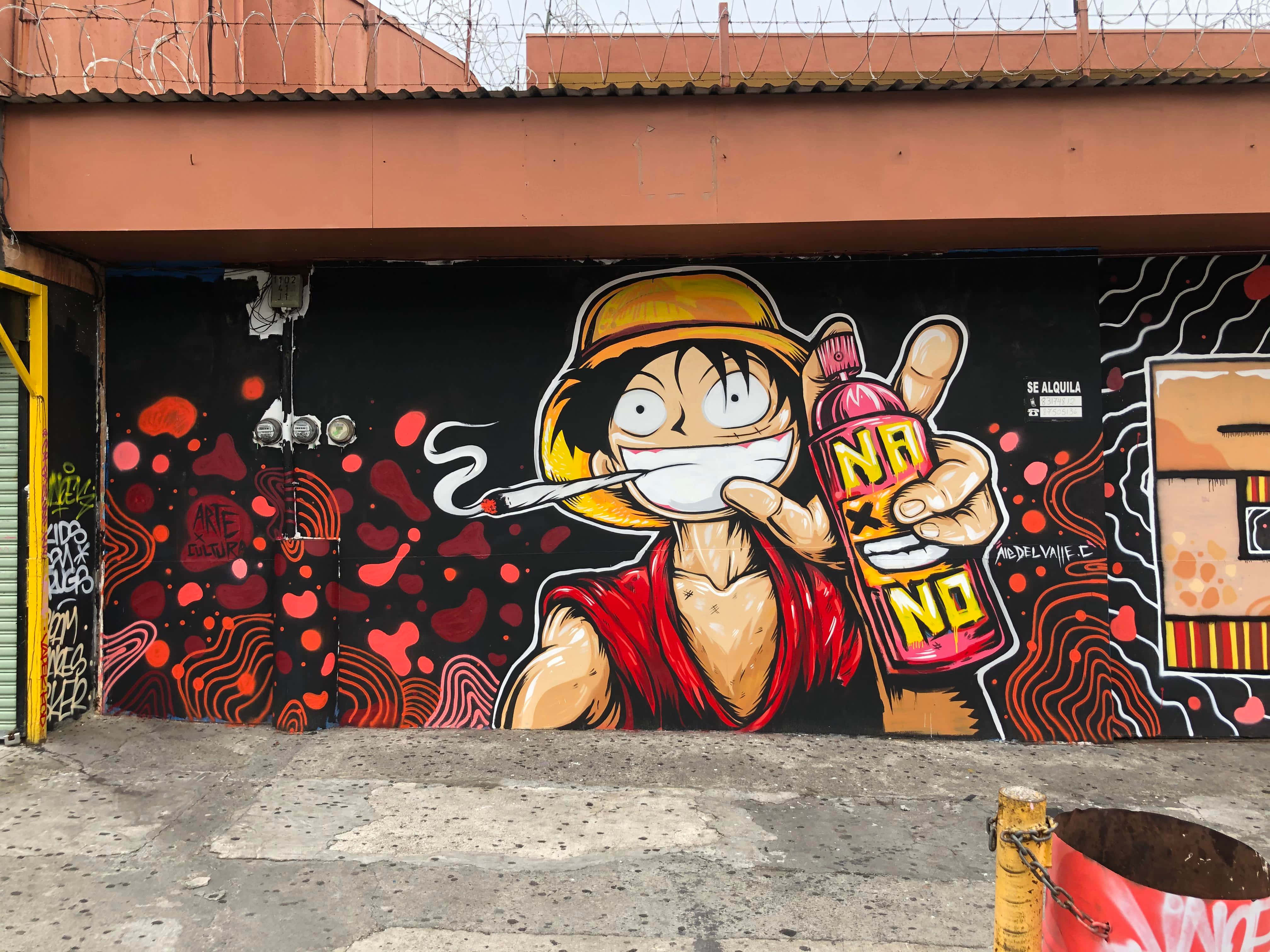 Graffiti Art 桌布 壁紙 — 一幅充滿活力的街頭壁畫，描繪動漫角色魯夫吸煙並手持噴漆罐，背景是帶有紅色抽象圖案的黑色牆壁。