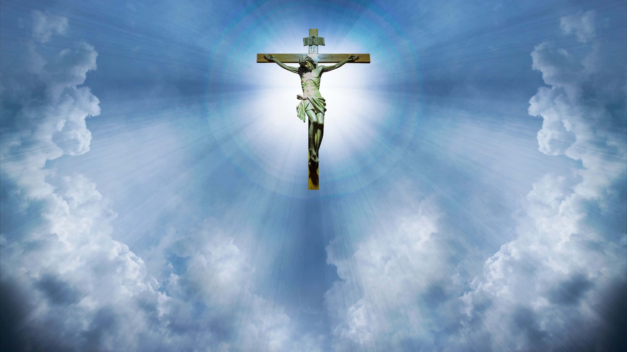 耶穌基督 桌布 壁紙 — 一幅光芒四射的 crucifixion 場景，耶穌在十字架上，背景是充滿雲彩和神聖光線的戲劇性藍天。