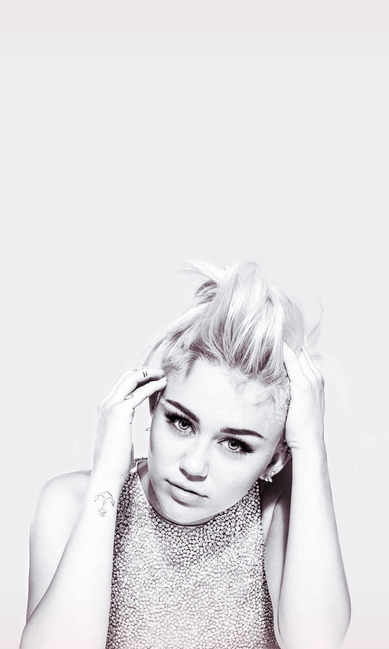miley 桌布 壁紙 — 一幅單色肖像，一名金髮蓬鬆的女性抱著頭，穿著有紋理的上衣，背景簡潔。