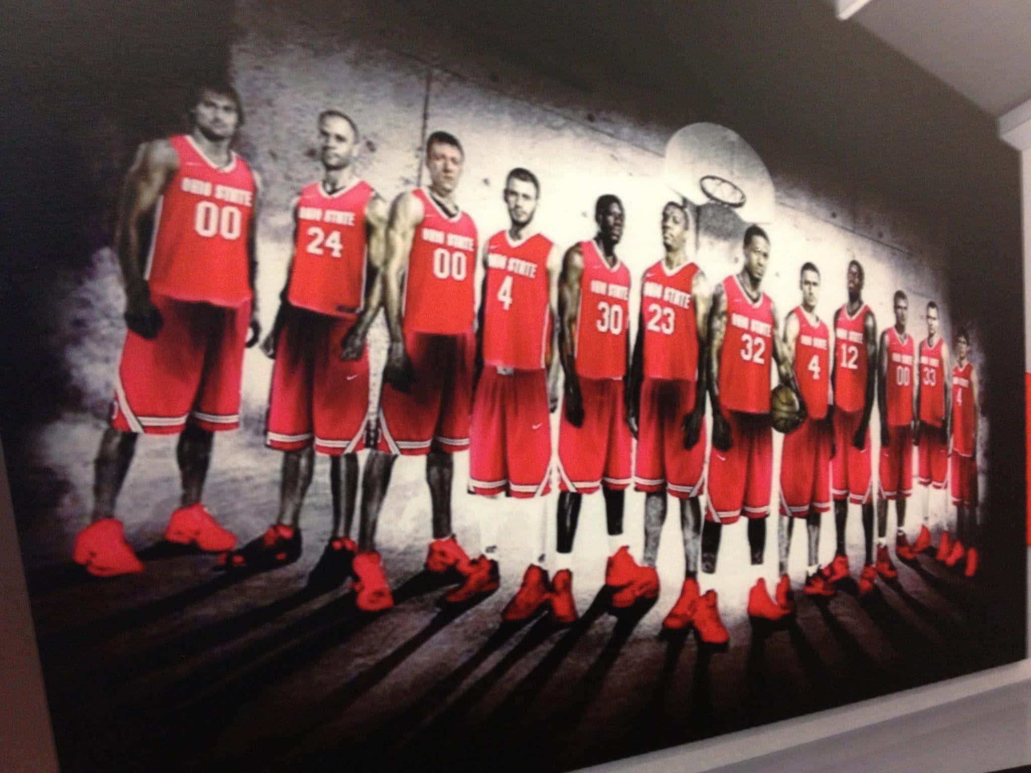 Cool Ohio State 桌布 壁紙 — 一幅壁畫，描繪俄亥俄州立大學籃球運動員身穿紅色球衣，在木地板上排成一排，燈光效果戲劇化。