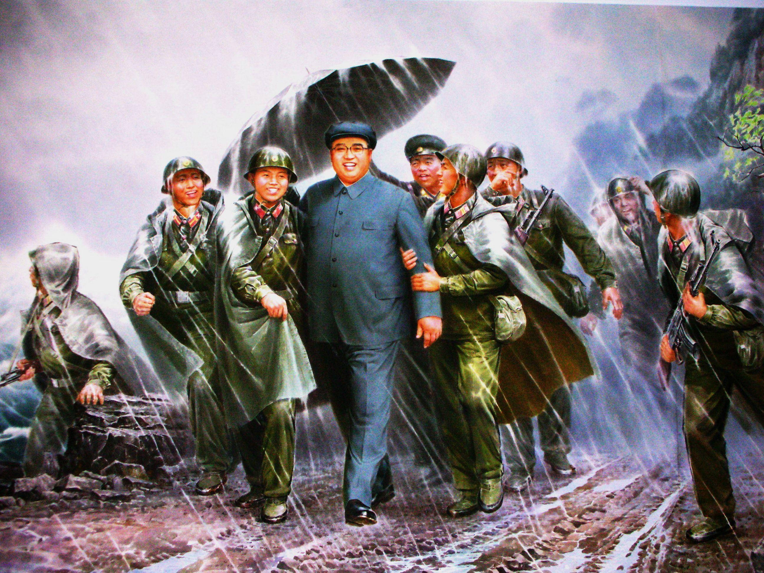 North Korea 桌布 壁紙 — 一幅壁畫描繪一個穿著藍色西裝的中心人物，與穿著雨衣微笑的士兵一起走過風雨交加的山口。