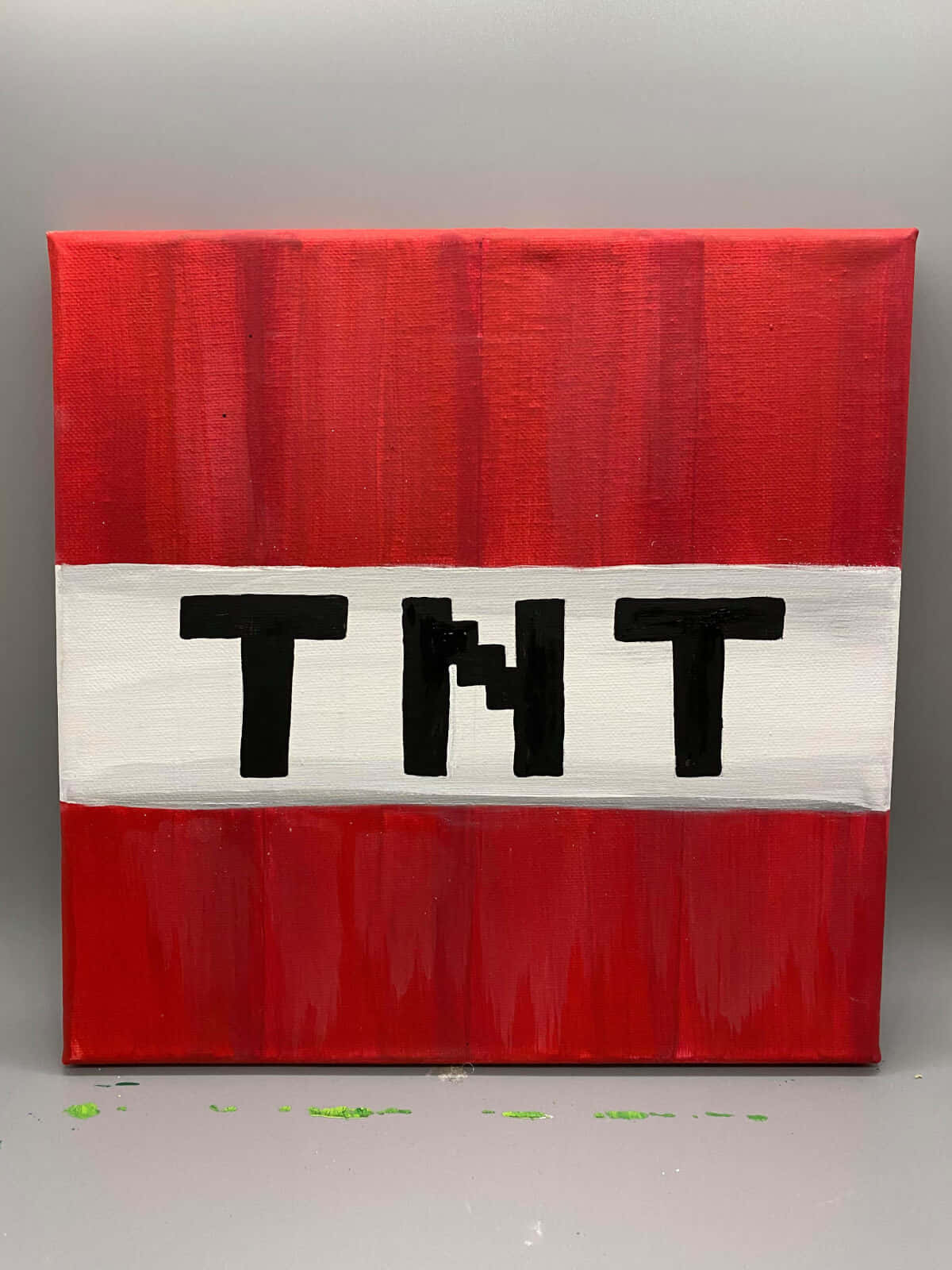我的世界 TNT 桌布 壁紙 — 一幅大膽的紅白畫布，上面有黑色的「TNT」字母，顯示筆觸和地板上的綠色油漆飛濺。
