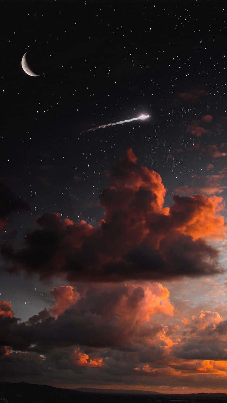 手機 桌布 壁紙 — 一幅天體場景，新月和流星在暮色中劃過熾熱的橙色雲層。