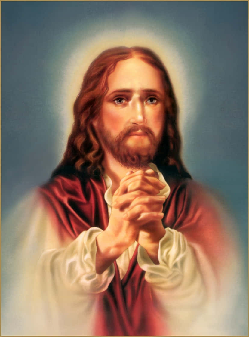 Jesus Praying 桌布 壁紙 — 一幅寧靜的耶穌基督肖像，長長棕色頭髮和鬍鬚，雙手合十祈禱，身穿紅色長袍內襯白衣，背景是柔和的藍色，帶有發光的光環。