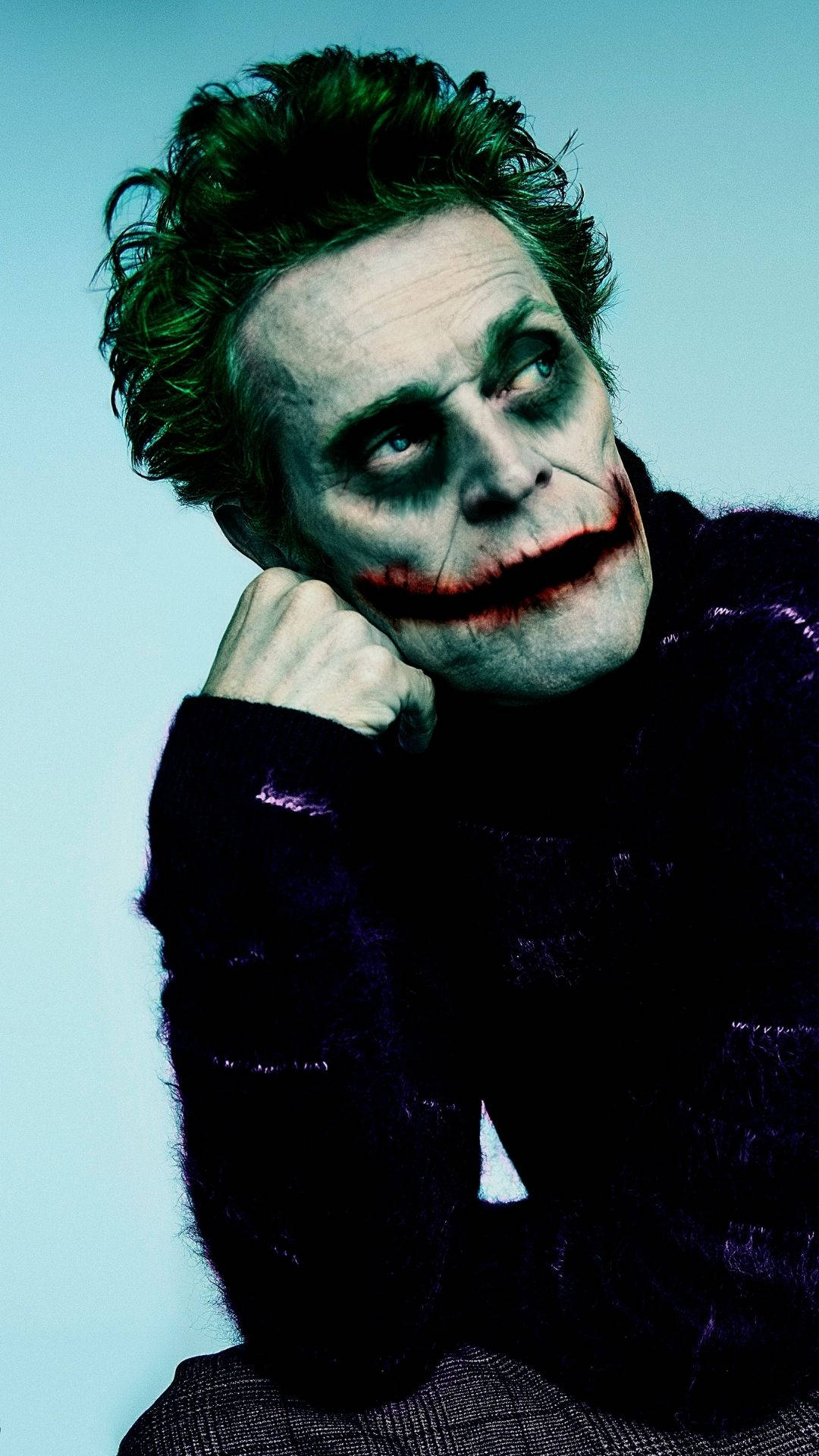 Willem Dafoe 桌布 壁紙 — 一幅小丑的威脅肖像，帶有模糊的紅唇和狂野的綠髮，背景是淡藍色。