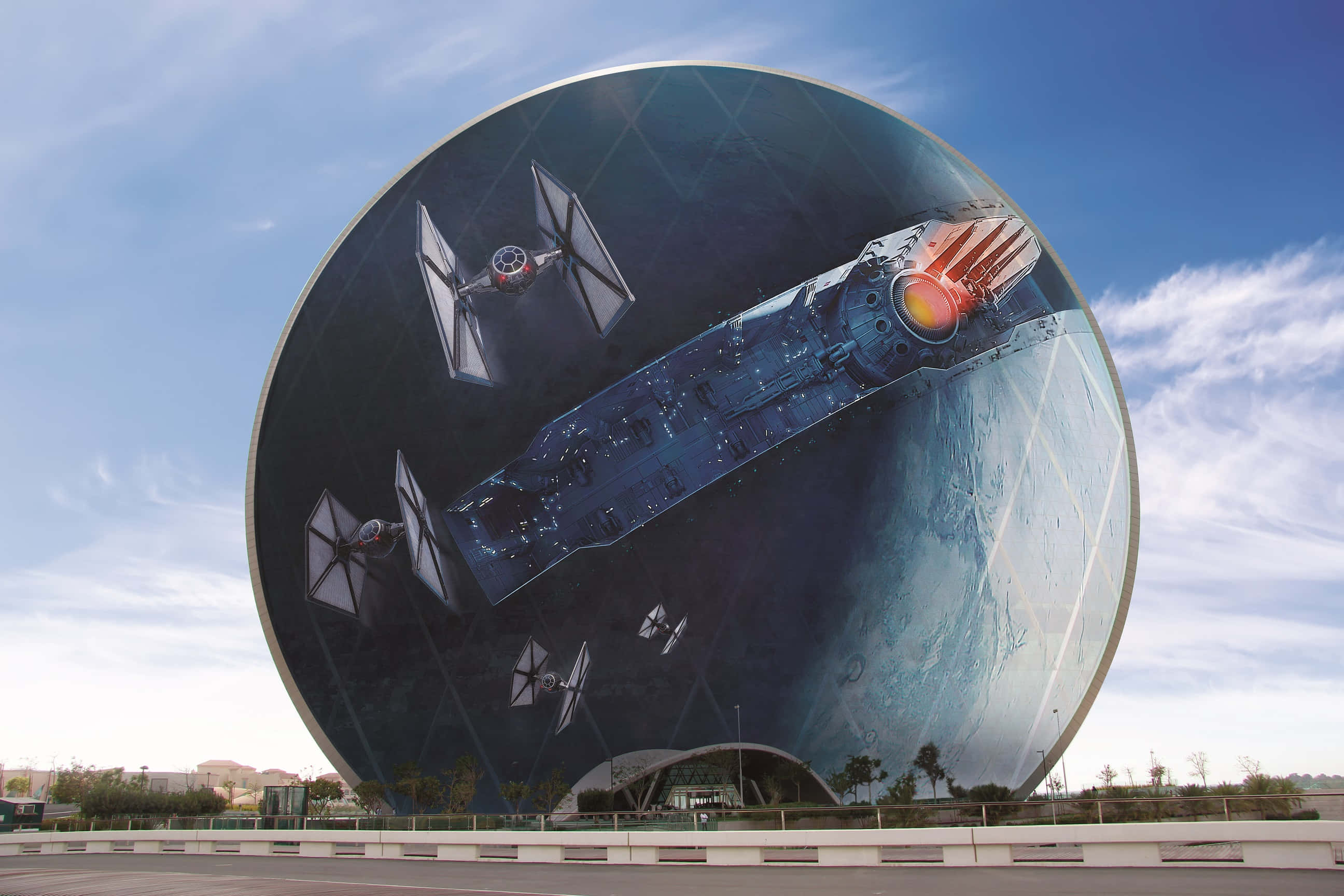 Starkiller Base 桌布 壁紙 — 一幅巨大的圓形壁畫描繪了《星際大戰》的TIE戰機和星際毀滅者，背景是星空，位於一座現代建築上，上方是藍天。