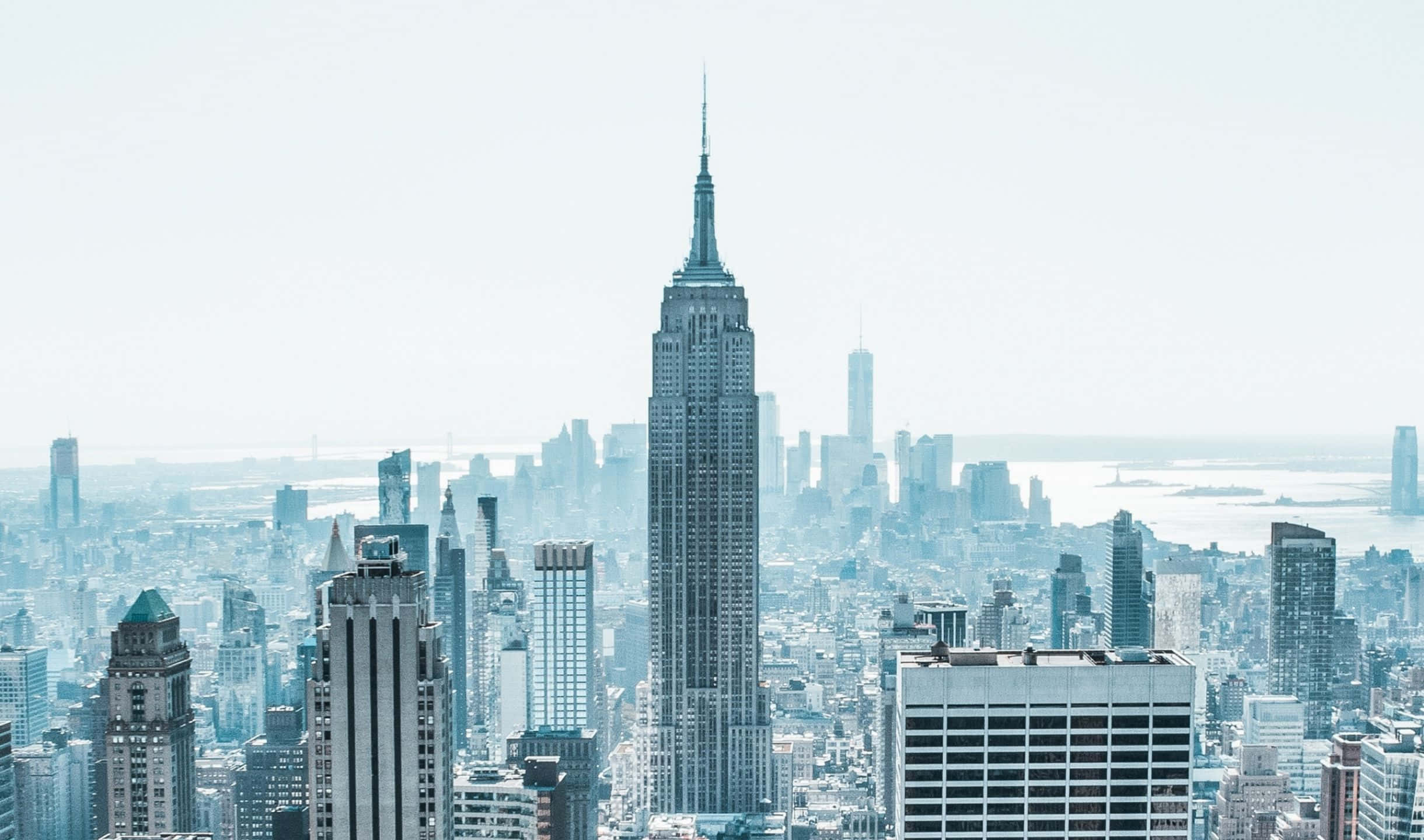 2440x1440 Empire State Building 桌布 壁紙 — 一幅帶有朦朧藍調的紐約市天際線鳥瞰圖，以帝國大廈為主導。