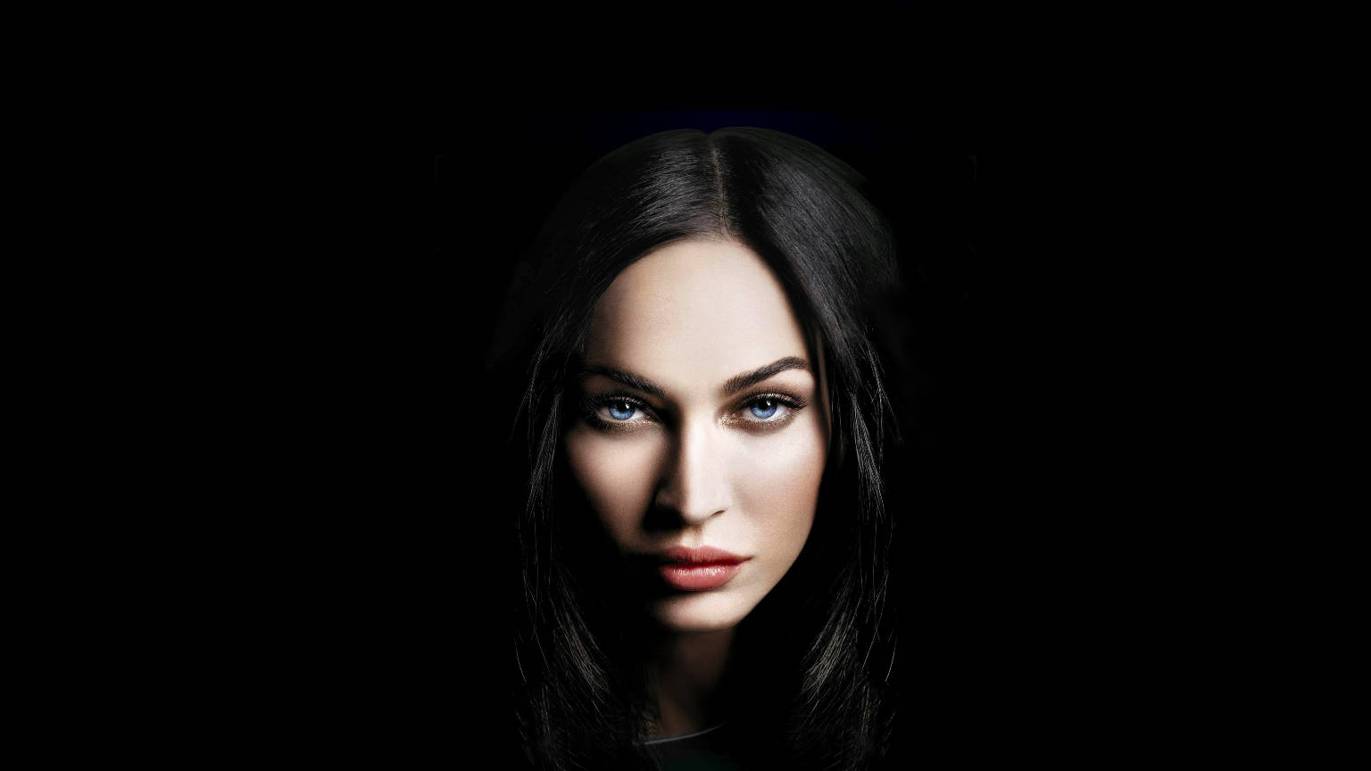 Woman Beautiful 桌布 壁紙 — 一幅引人注目的肖像，一位擁有銳利藍眼睛和深色頭髮的女性，背景為純黑色。