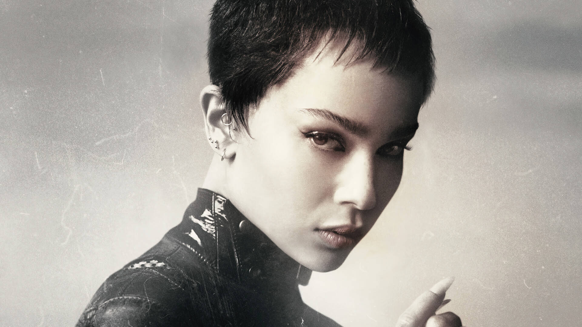 Catwoman 桌布 壁紙 — 一幅引人注目的肖像，人物留著短黑髮，眼神銳利，穿著質感外套，背景為柔和的灰色。