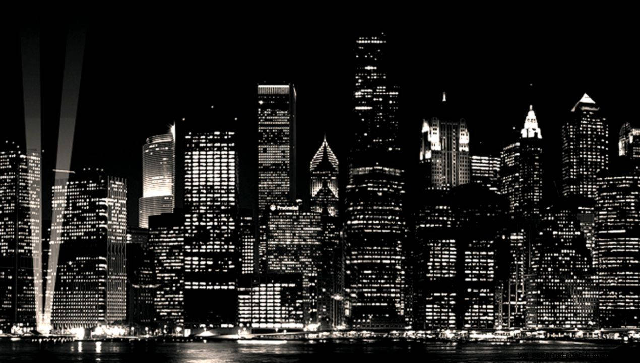 New York 桌布 壁紙 — 一幅引人注目的黑白夜景城市景觀，高聳的摩天大樓帶有發光的窗戶，倒映在水面上。