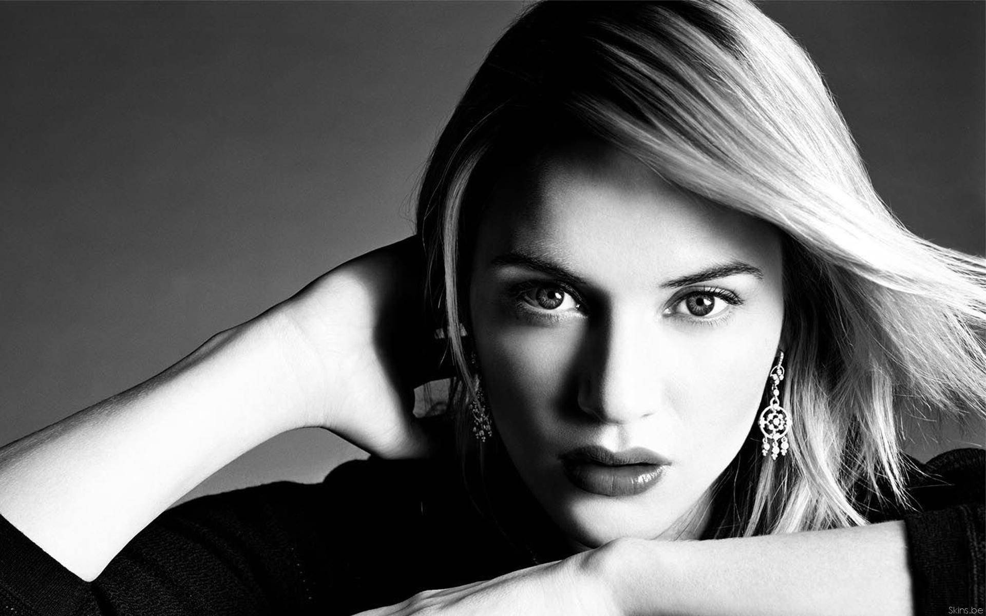 Kate Winslet 桌布 壁紙 — 一幅引人注目的黑白肖像，一位金髮女子眼神銳利，下巴擱在手上。
