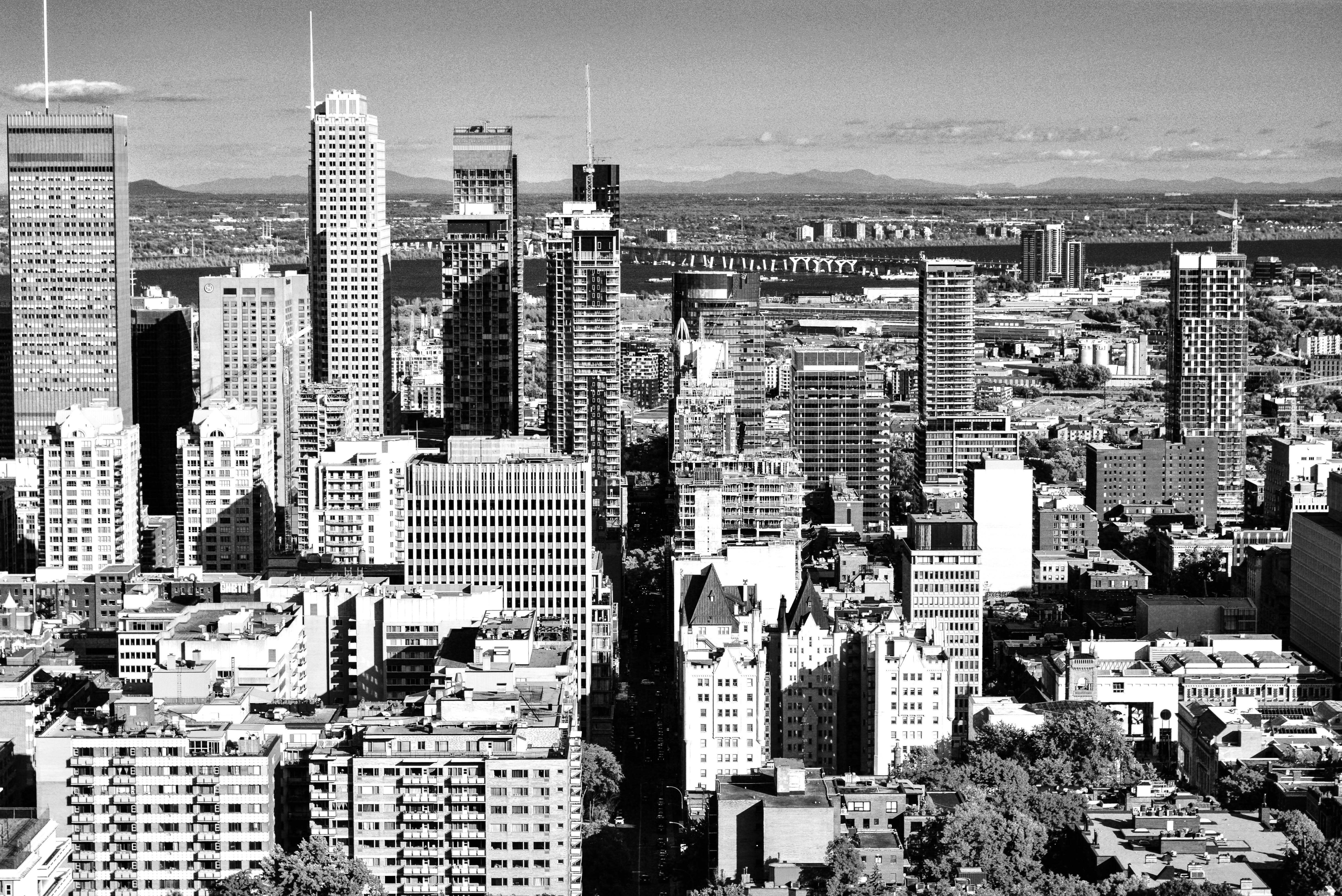 Montreal 桌布 壁紙 — 一幅引人注目的黑白航拍圖，展現密集的城市天際線，高聳的摩天大樓與歷史建築在部分多雲的天空下。