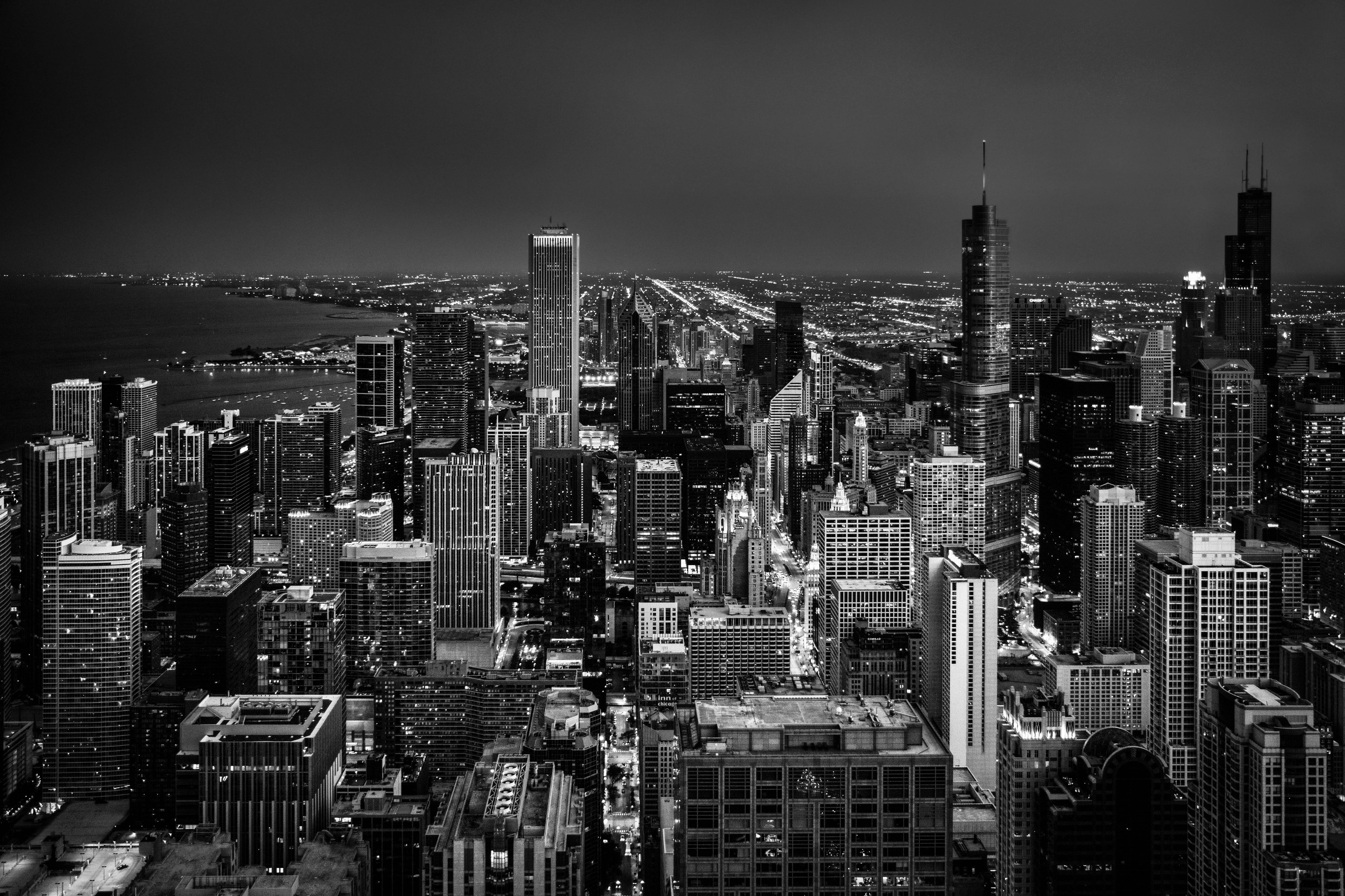 Dark 4K 桌布 壁紙 — 一幅引人注目的黑白鳥瞰圖，展現了夜晚廣闊的城市景觀，摩天大樓燈火通明，街道閃爍發光。