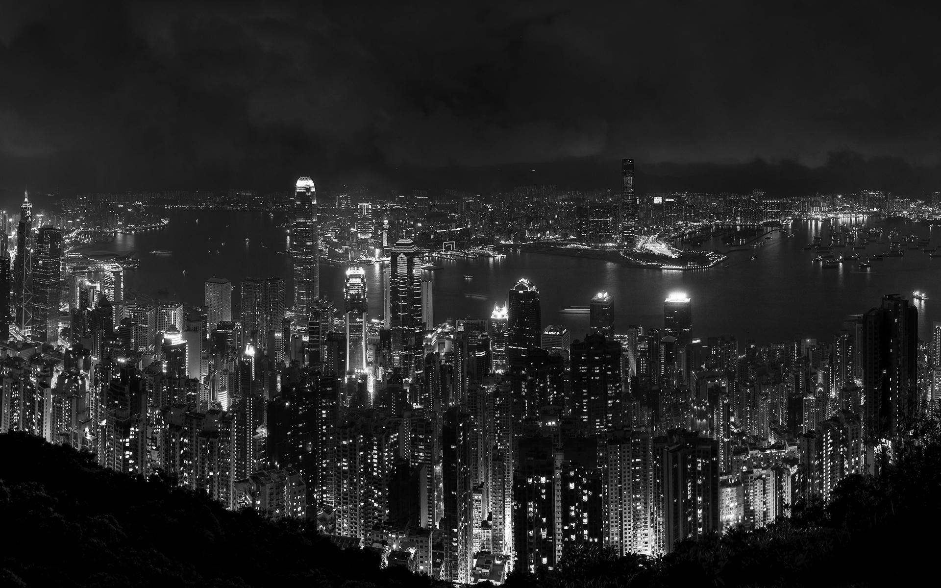 城市風景 桌布 壁紙 — 一幅引人注目的黑白鳥瞰圖，展現了夜晚密集燈光的城市景觀，高聳的摩天大樓和閃爍的港灣。