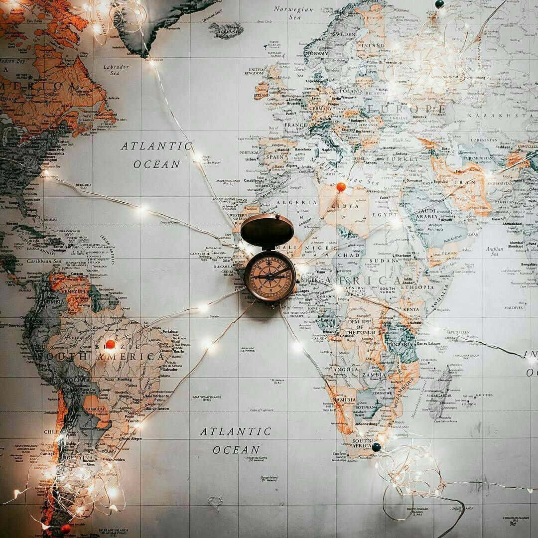World Map Aesthetic 桌布 壁紙 — 一幅復古世界地圖，中央裝飾著閃爍的童話燈和經典黃銅指南針。