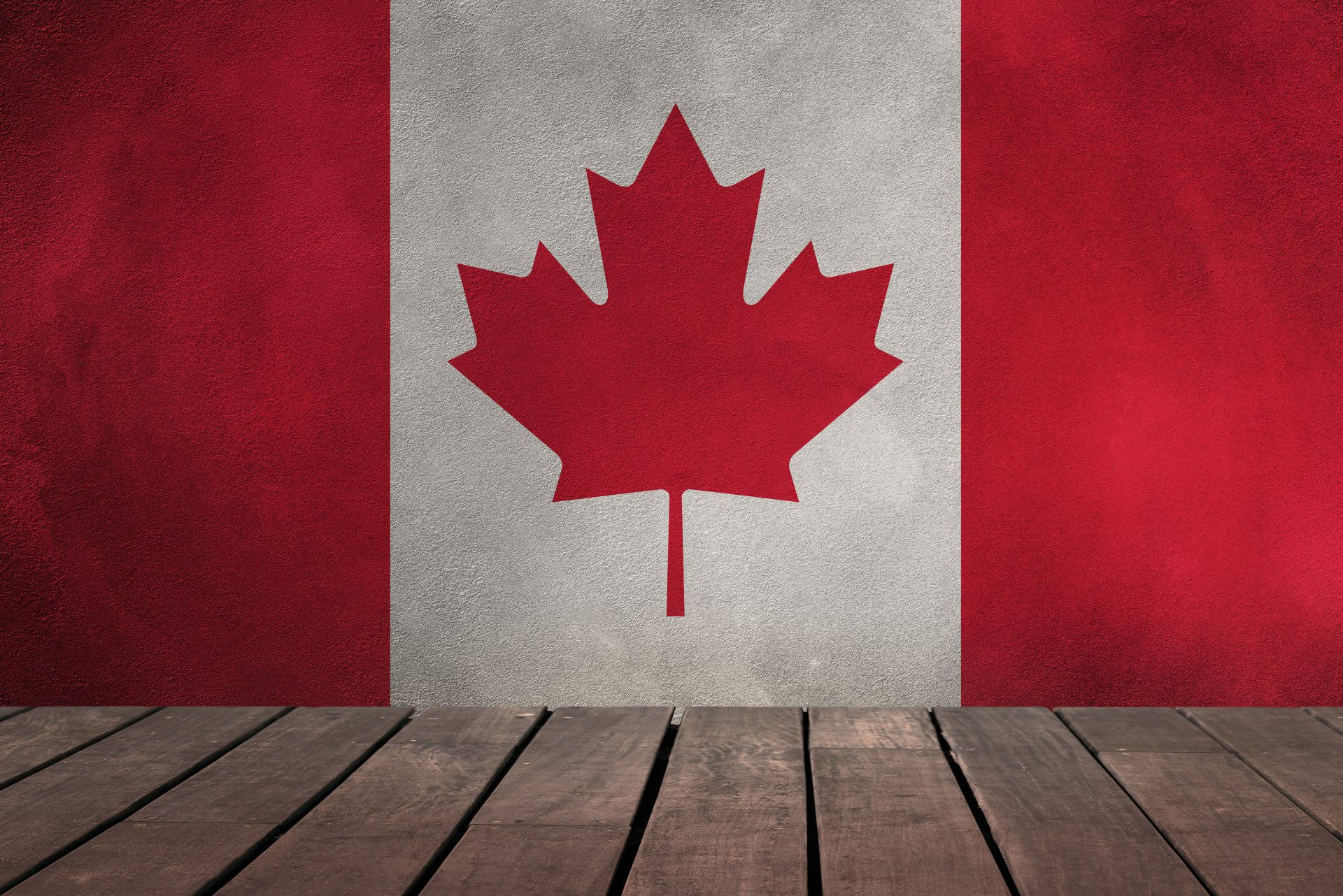 Canada Flag 桌布 壁紙 — 一幅有紋理的加拿大國旗畫在混凝土牆上，前景是木地板。