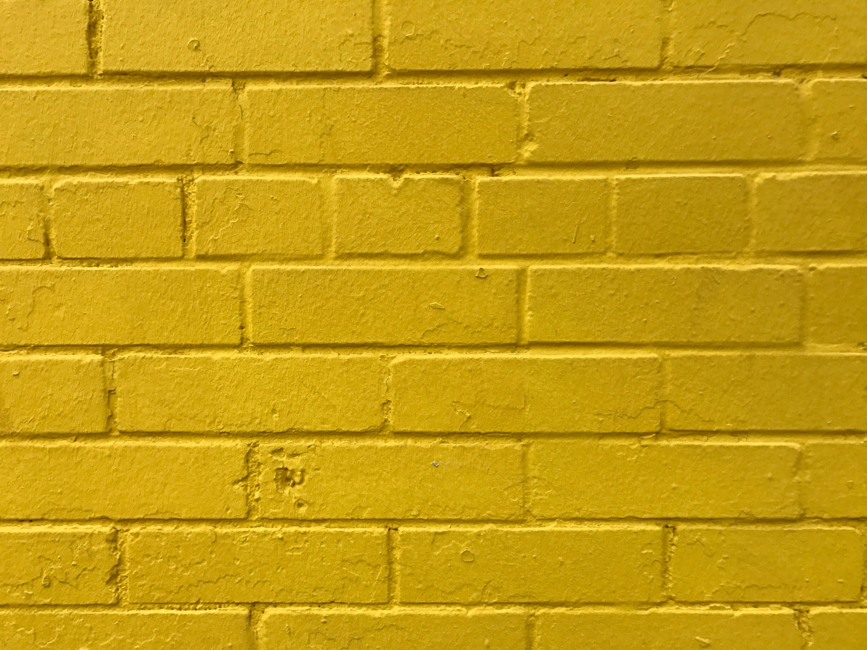 Brick 桌布 壁紙 — 一幅有紋理的黃色磚牆特寫，可見砂漿線和細微的表面瑕疵。