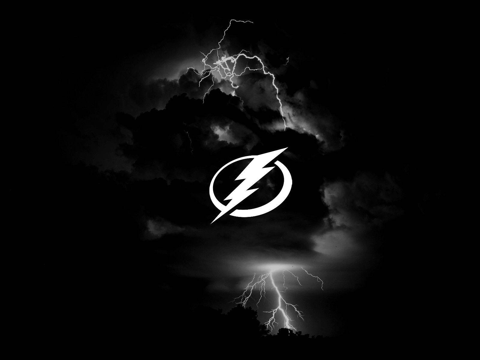 坦帕灣閃電 桌布 壁紙 — 一幅清晰的黑白暴風雨場景，生動的閃電照亮烏雲，中央有一個突出的白色閃電標誌。