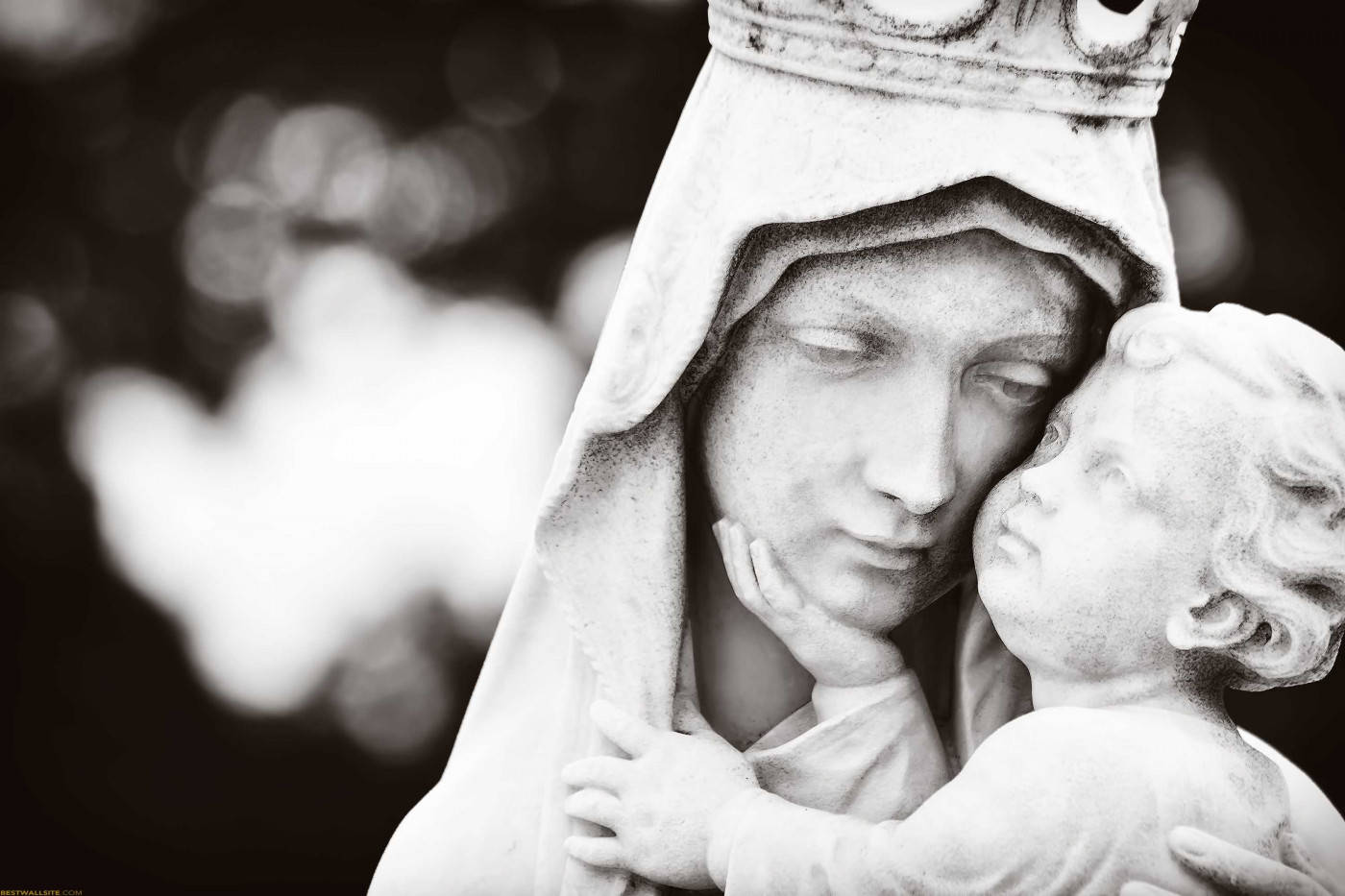 Virgin Mary 桌布 壁紙 — 一幅溫柔的黑白雕像，聖母瑪利亞懷抱嬰兒耶穌，背景帶有柔和散景效果。