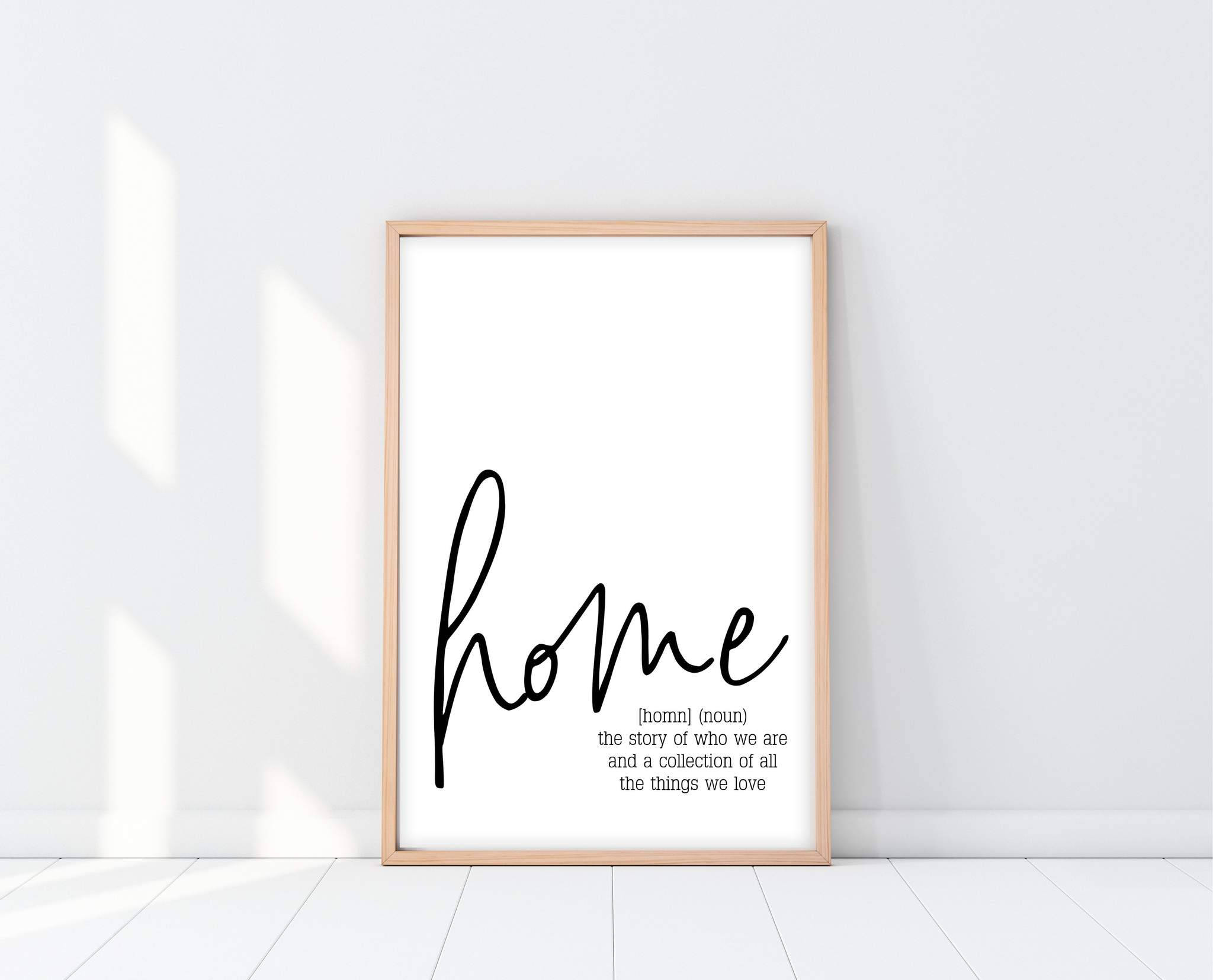 Home 桌布 壁紙 — 一幅簡約風格的裱框牆壁藝術品，上面以優雅字體寫著「home」一詞及其定義，在白色牆壁和地板上投下柔和陰影。