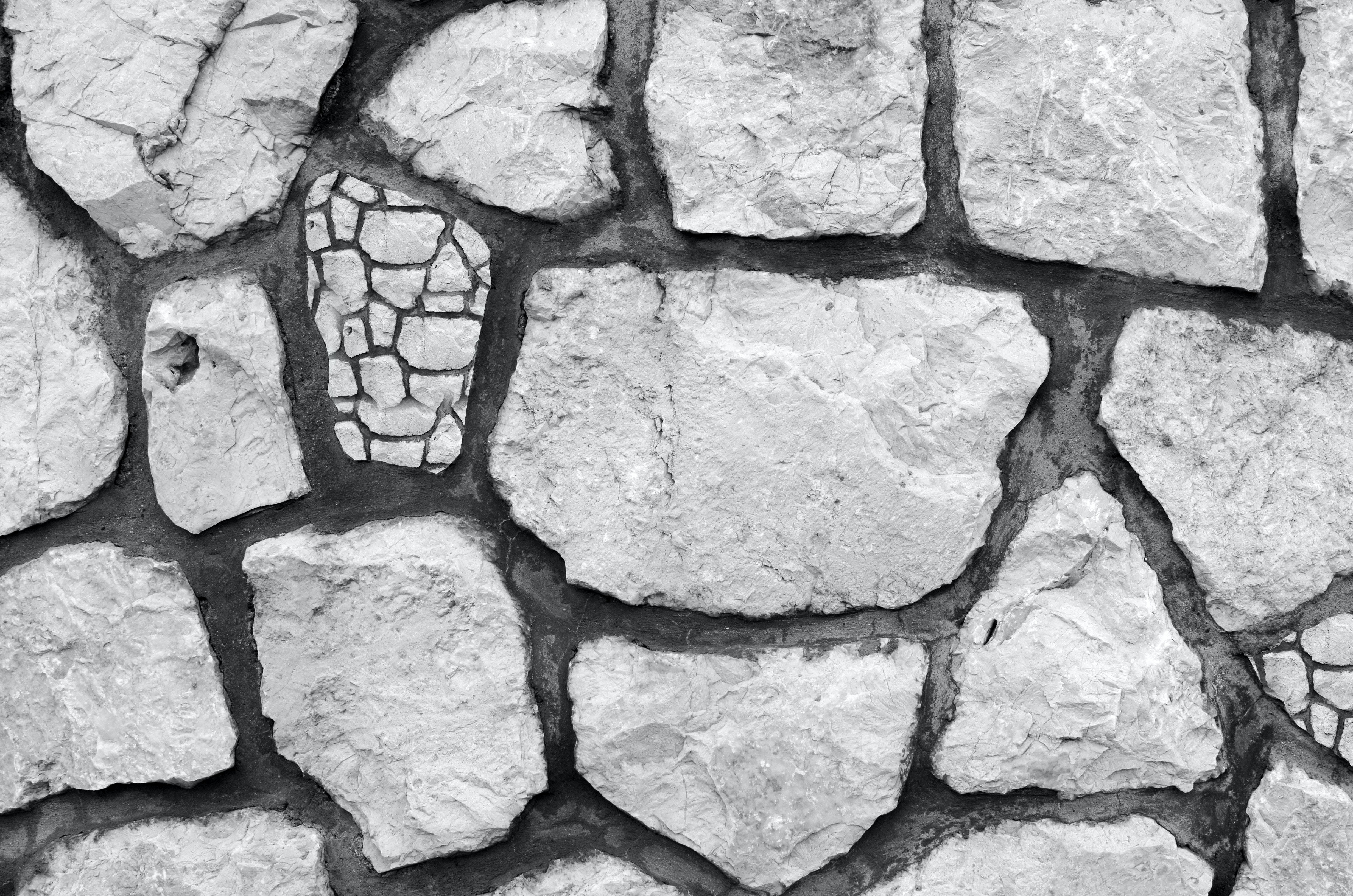 Stone Wall 桌布 壁紙 — 一幅粗糙石牆的單色特寫，石頭形狀各異，砂漿線條深色。