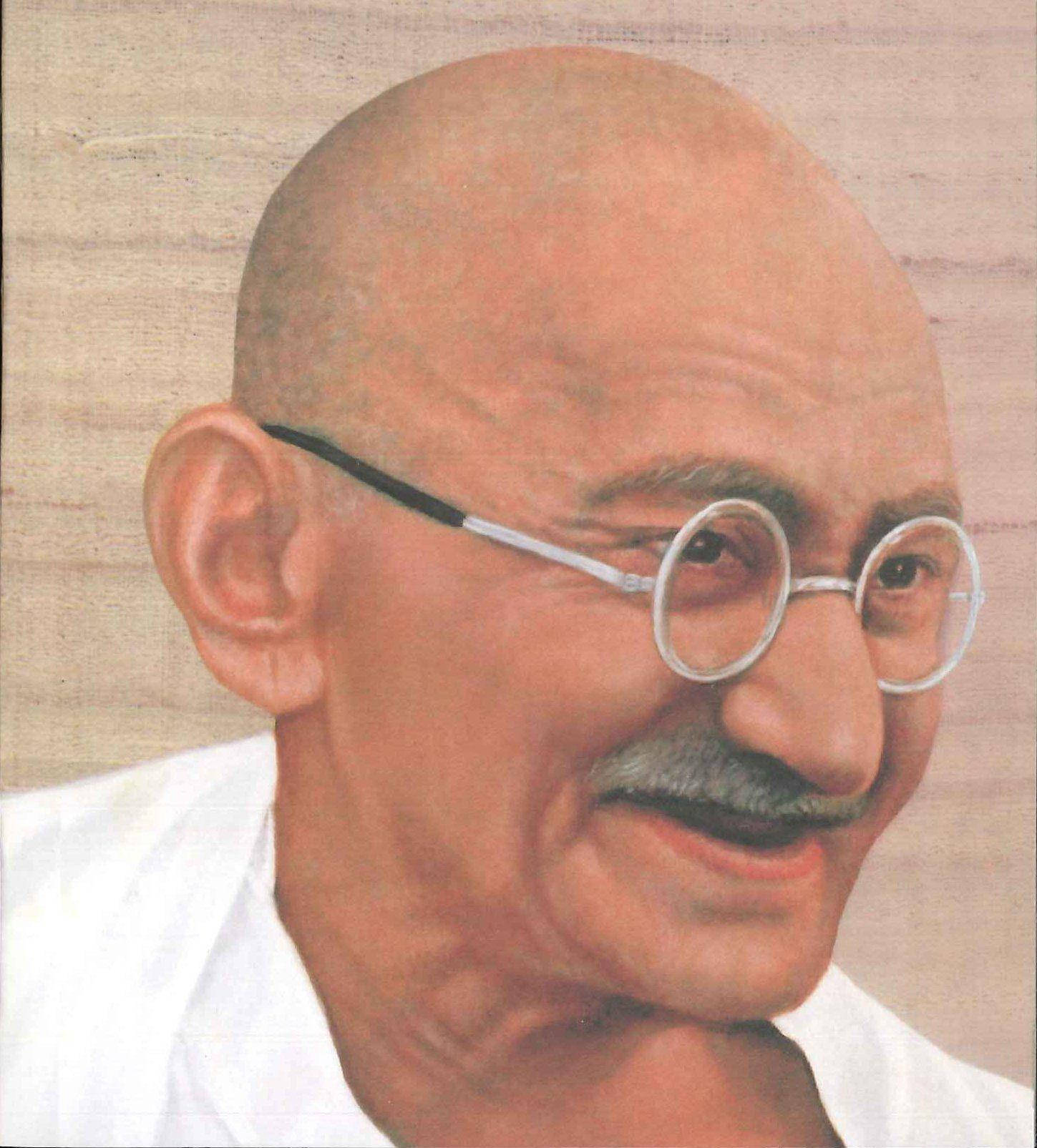 Mahatma Gandhi 桌布 壁紙 — 一幅聖雄甘地的寧靜肖像，戴著圓形眼鏡，面帶溫柔微笑，背景為有紋理的米色。