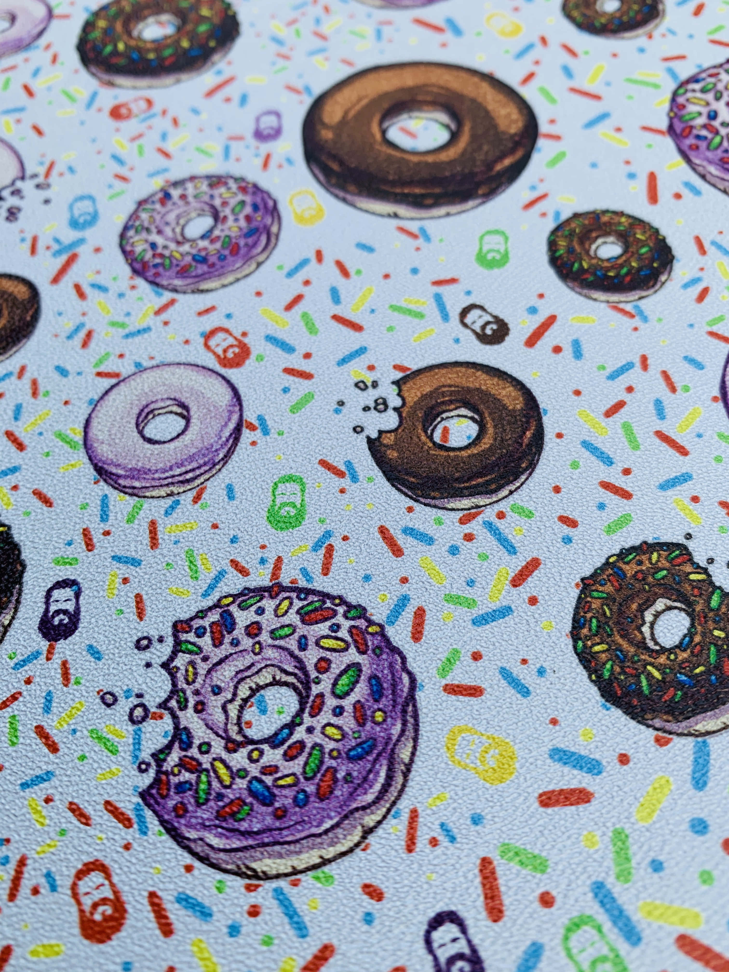 Cute Donut 桌布 壁紙 — 一幅色彩繽紛的插圖，展示各種甜甜圈，上面撒滿彩色糖粒，散落在淺藍色背景上。